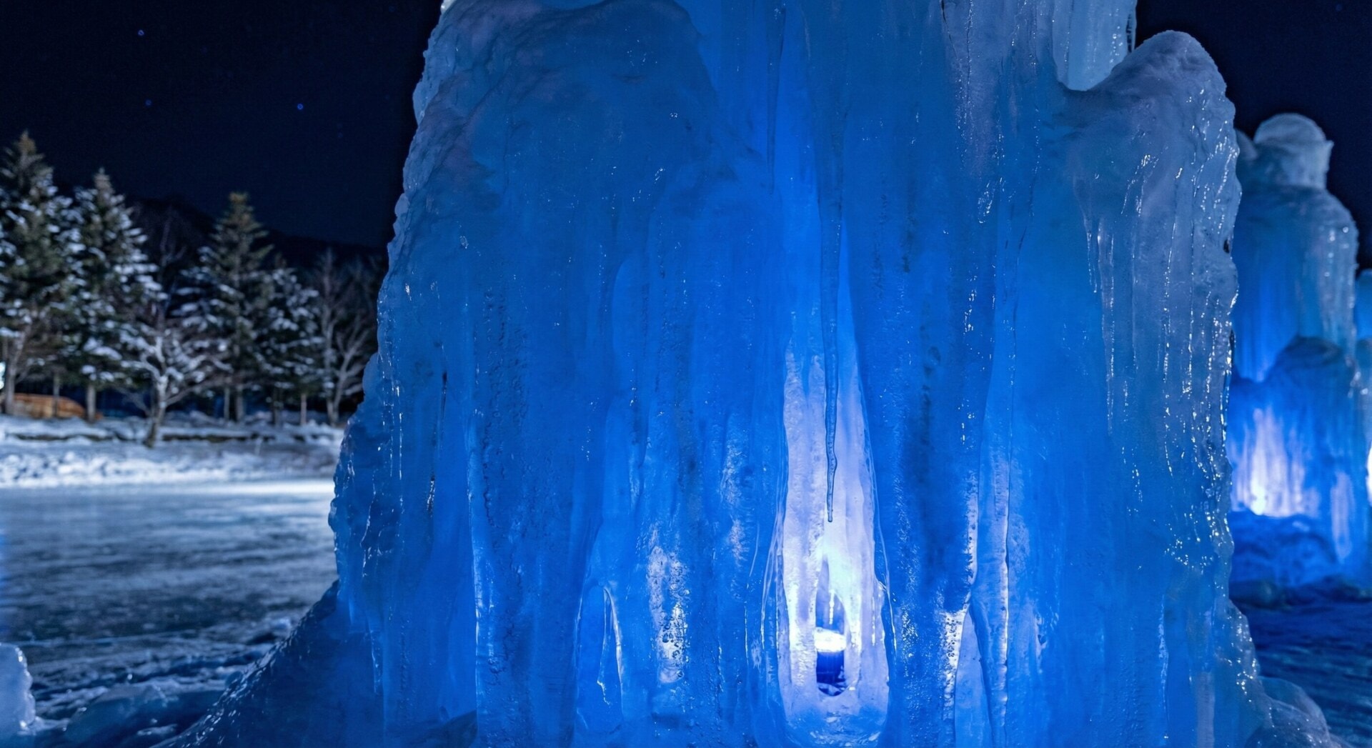 Towering natural ice sculptures glowing with the signature Shikotsu Blue color during the winter festival.
