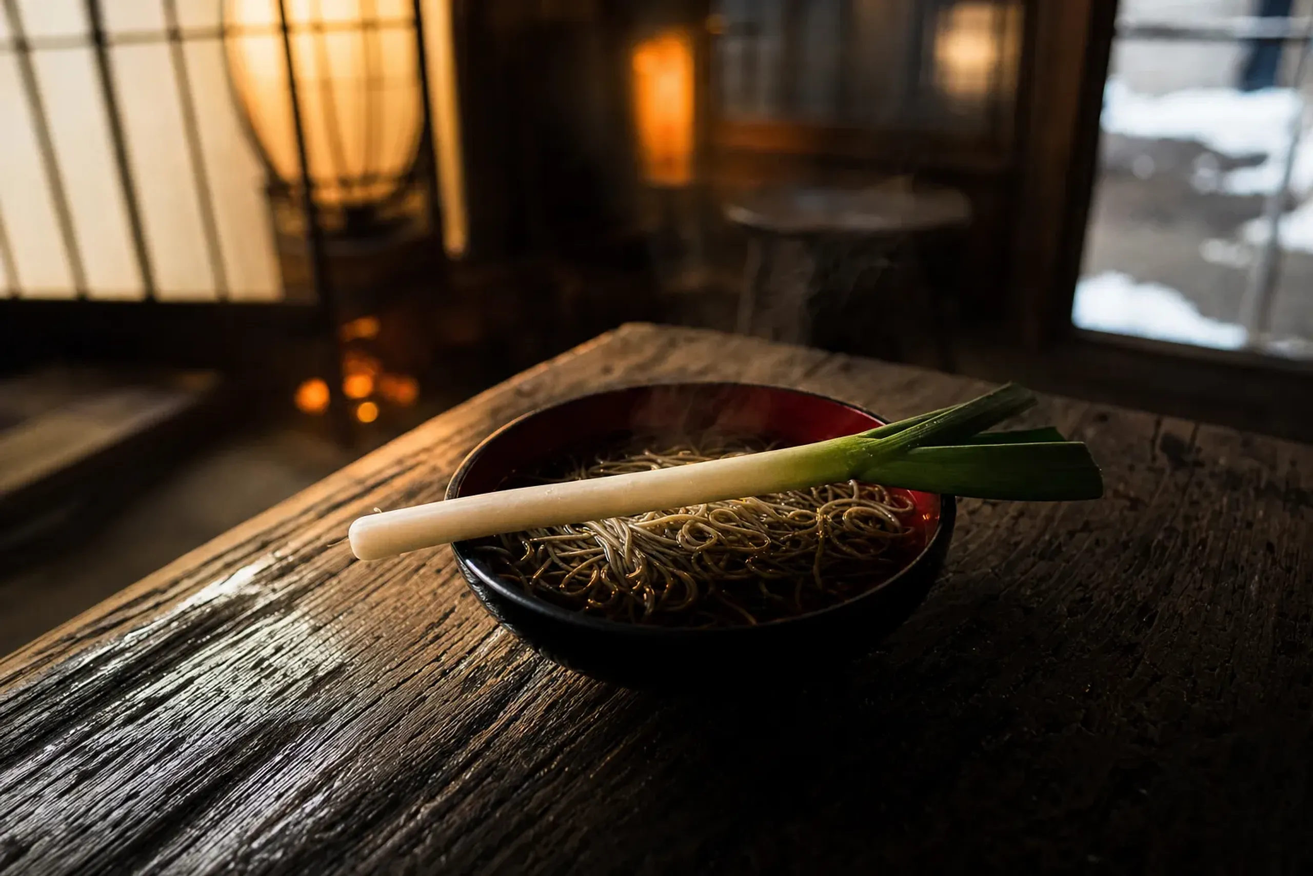 a lacquer bowl of negi soba with buckwheat noodles and a single whole leek used as an eating utensil, served at Ōuchi-juku
