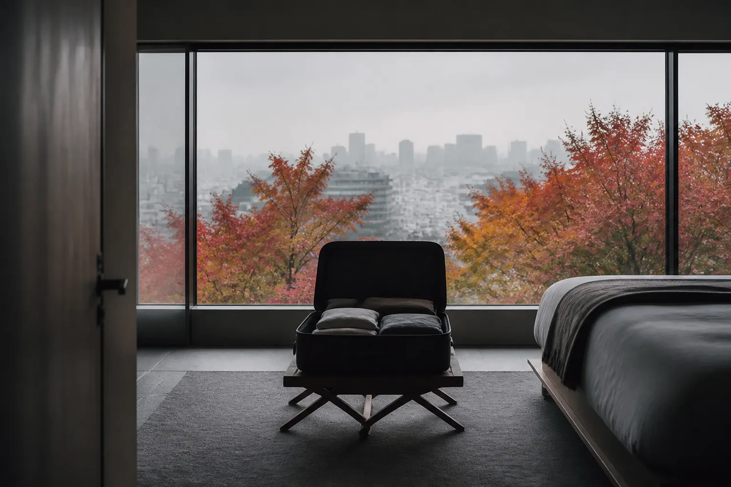 Open suitcase on a rack in a Tokyo hotel room with the city skyline through the window