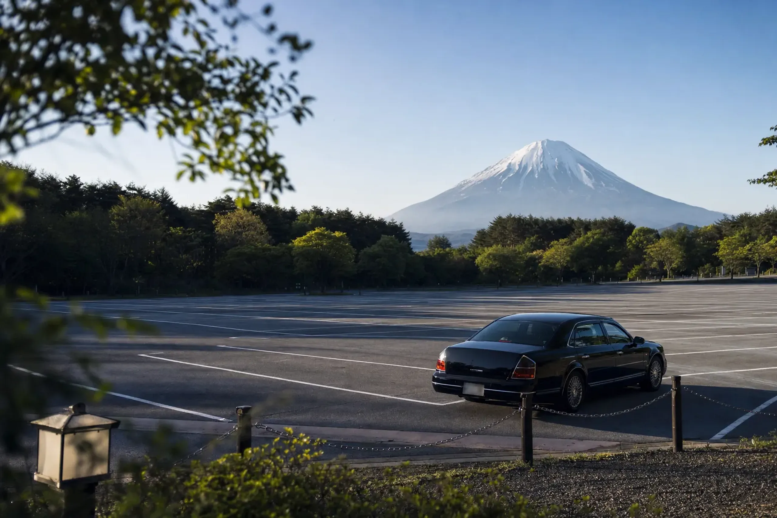 The largely empty Fuji Motosuko Resort parking lot at the 8:00 morning opening, a single chauffeured car parked near the entrance before the tour buses arrive