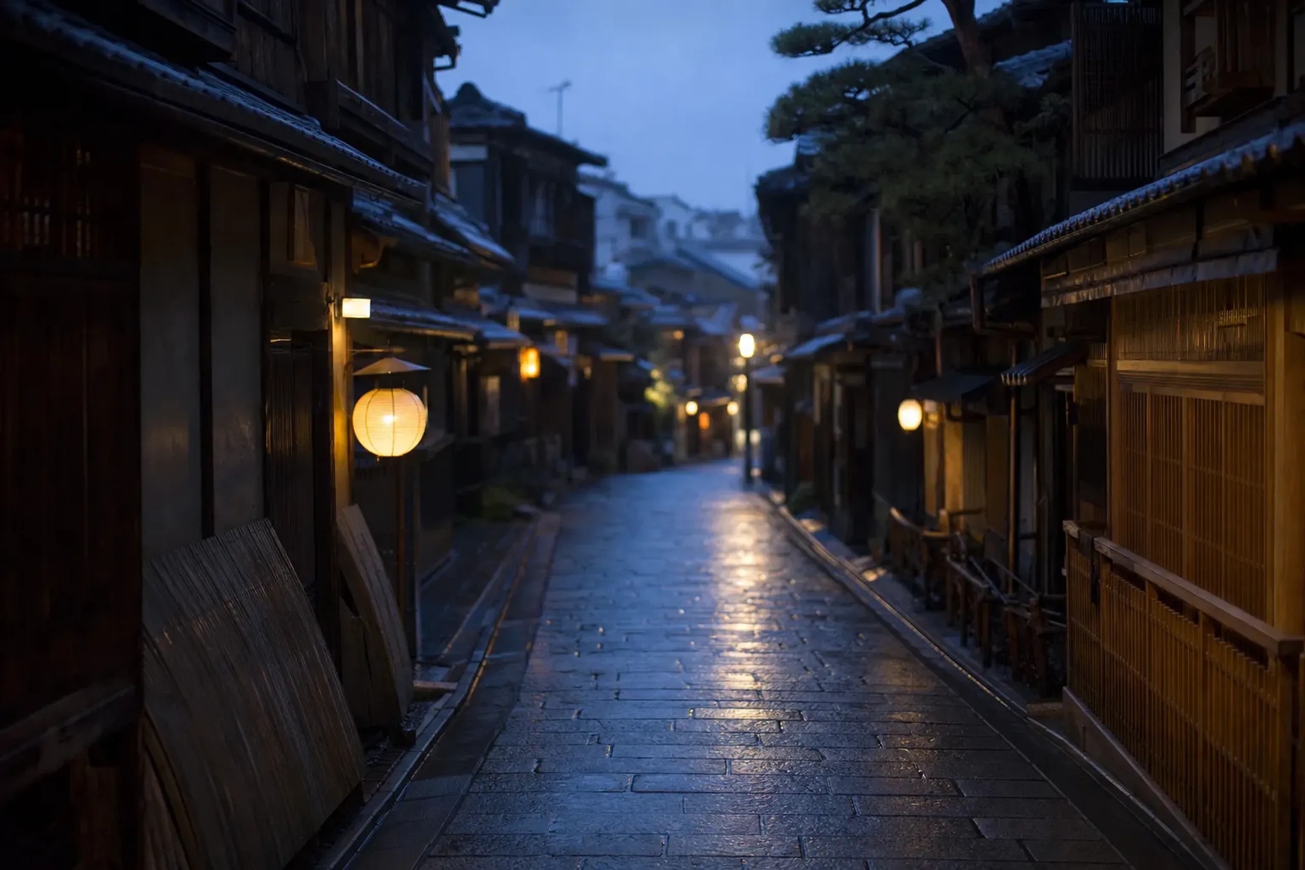 Quiet wooden machiya lane in Gion Kōbu, Kyoto, lit by lanterns in early morning