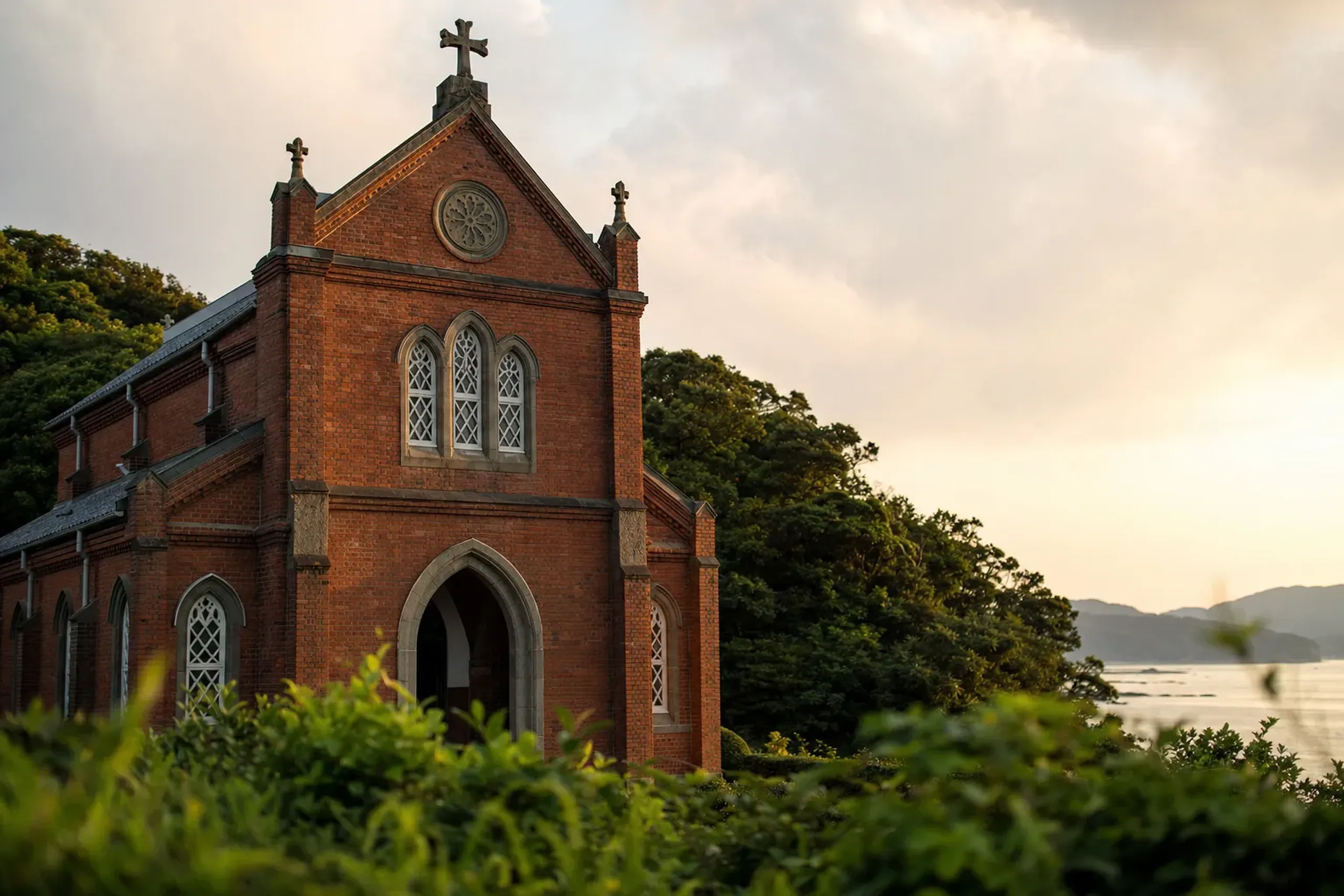 The red-brick Western-style facade of Dōzaki Church on Fukue Island, set near the coast against quiet surrounding greenery