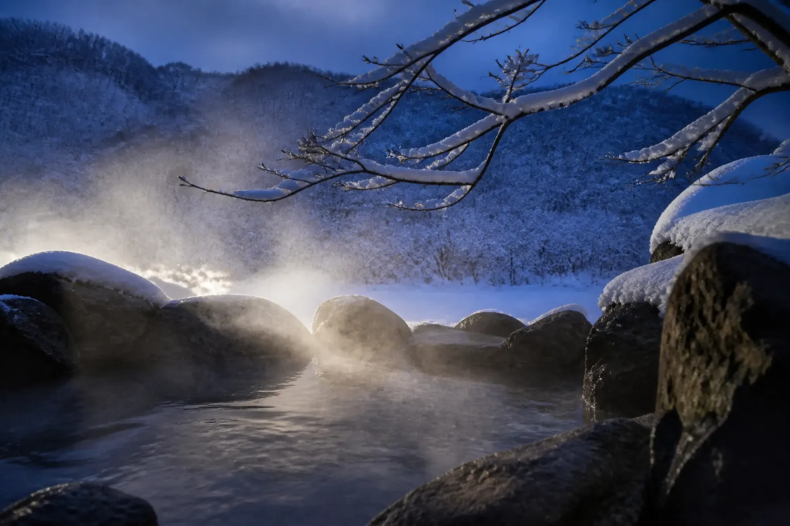 Steaming outdoor hot spring bath surrounded by snow