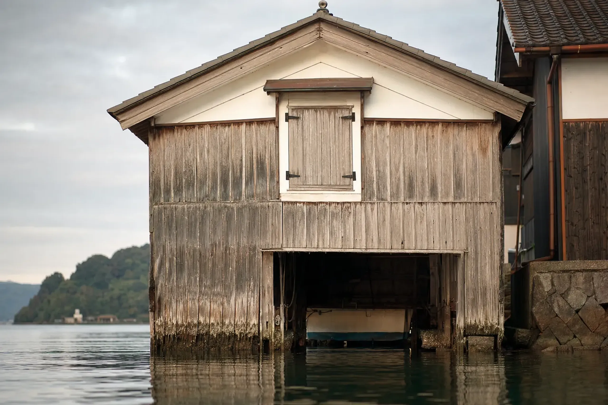 An 18th-century style two-storey timber funaya boathouse at the Ine waterline with its door opening directly onto the bay