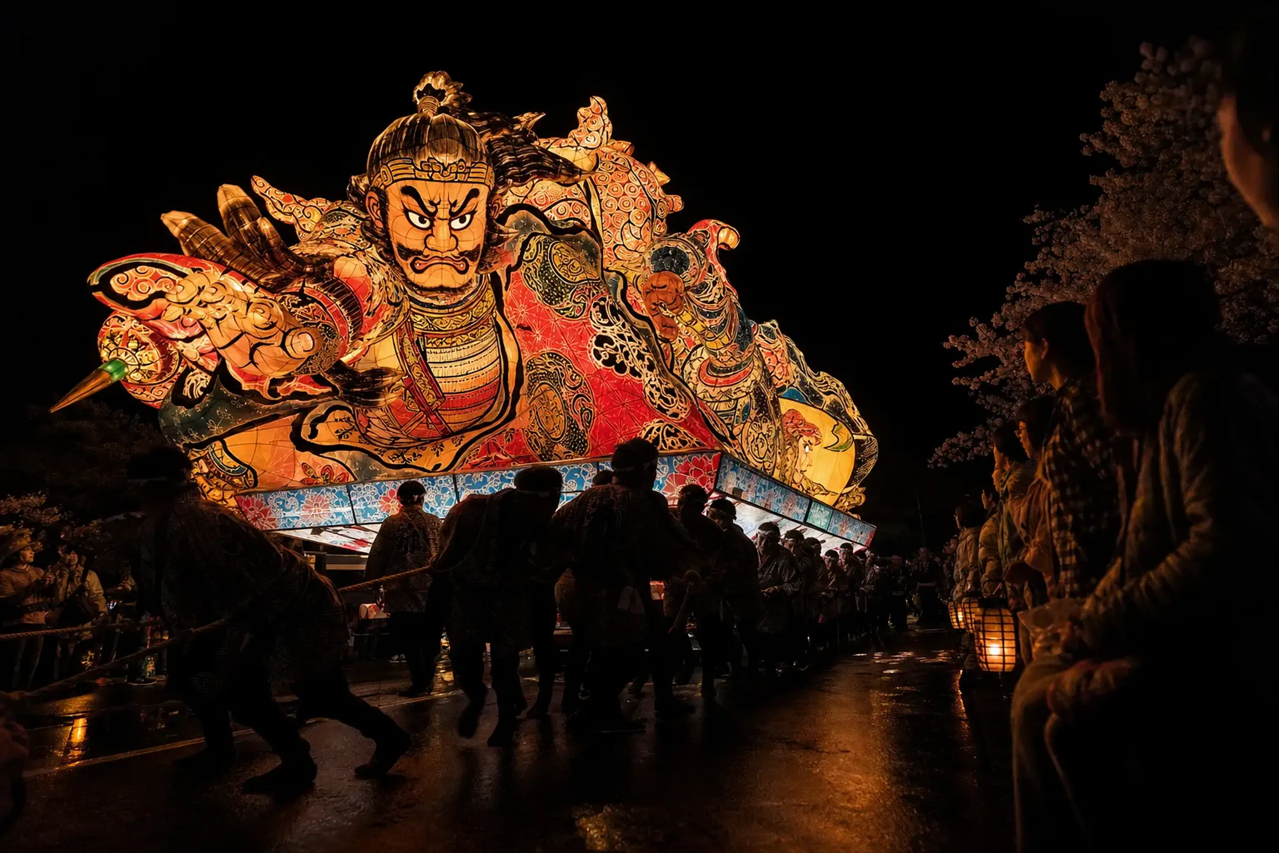 Glowing painted Nebuta float moving through an Aomori street at night during the August festival