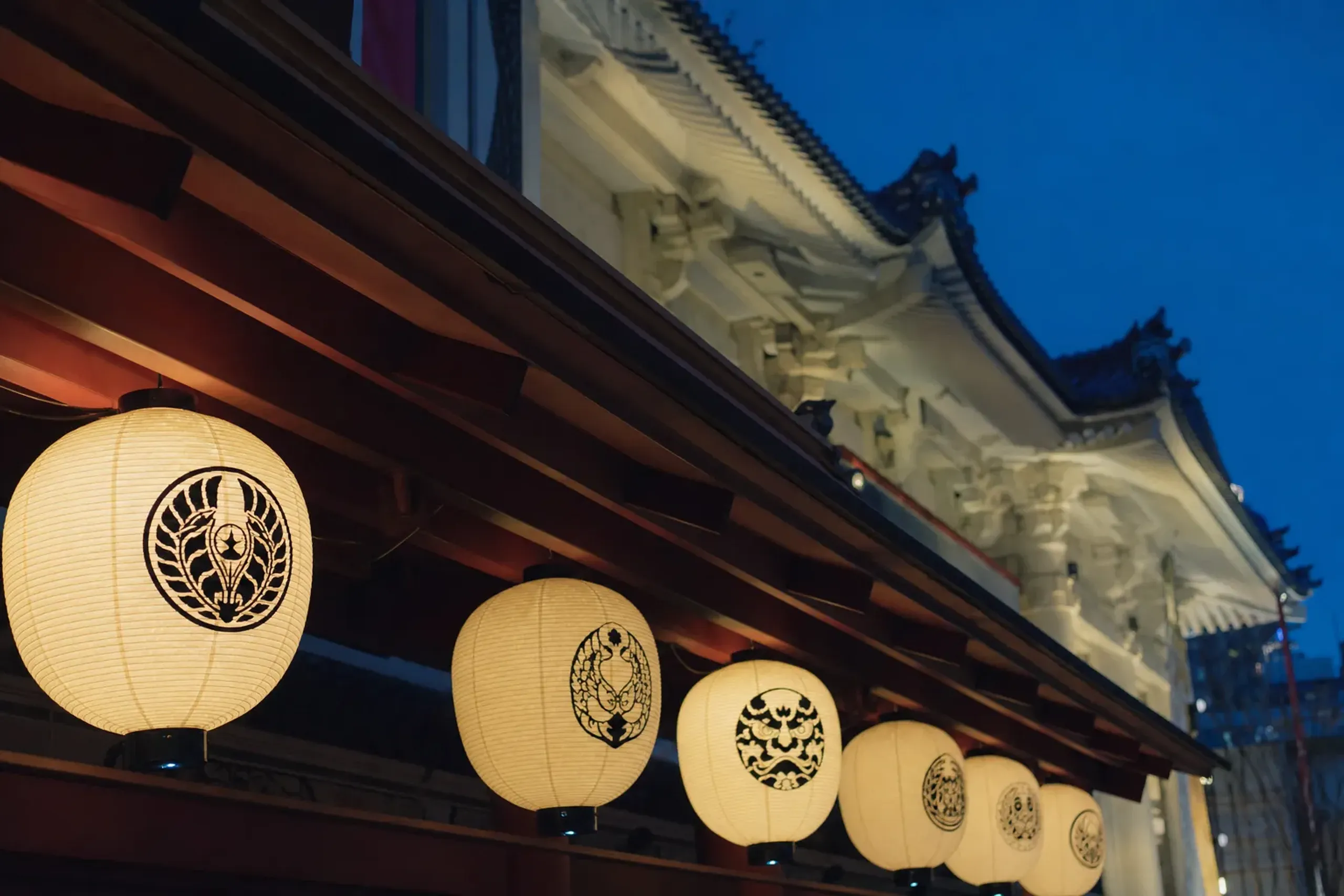 The illuminated Kabukiza entrance canopy at dusk with hanging paper lanterns bearing kabuki actor crests