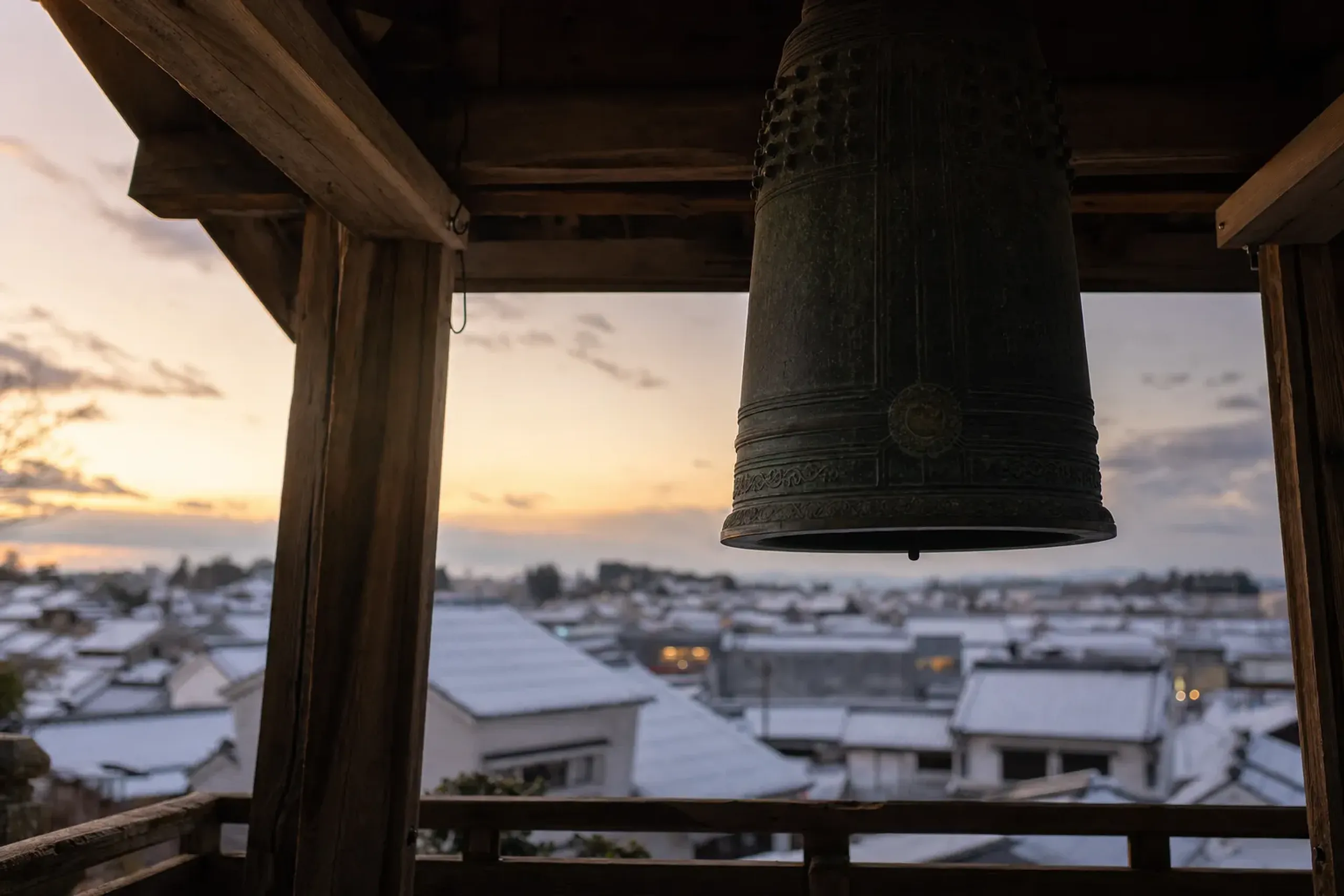 The suspended bronze bell inside the top tier of Kawagoe's 16-meter Toki no Kane tower, framed against tiled kurazukuri roofs