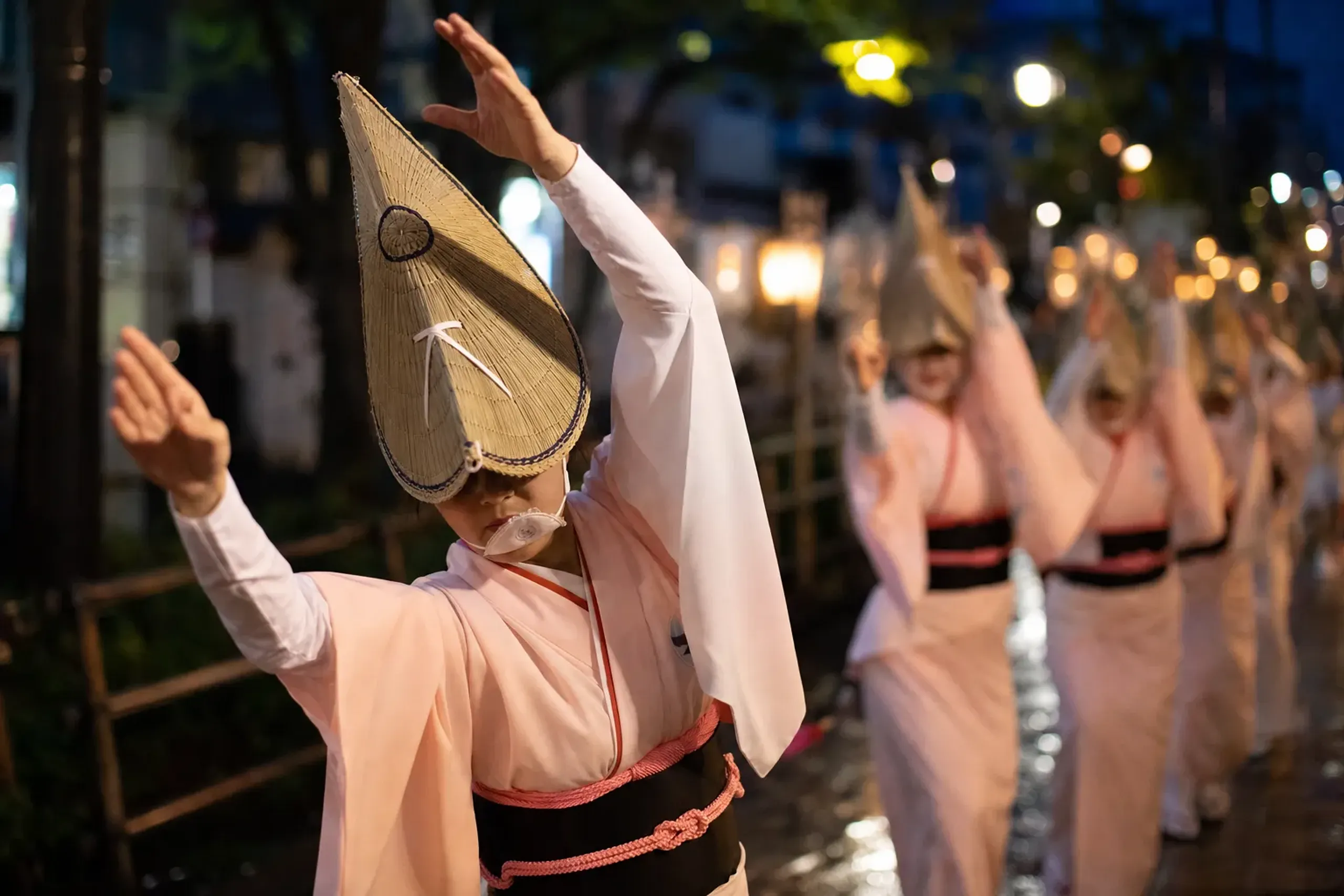 Awa Odori dancers of Tokushima performing bare-handed with open, flowing arms in a nighttime street procession on Shikoku