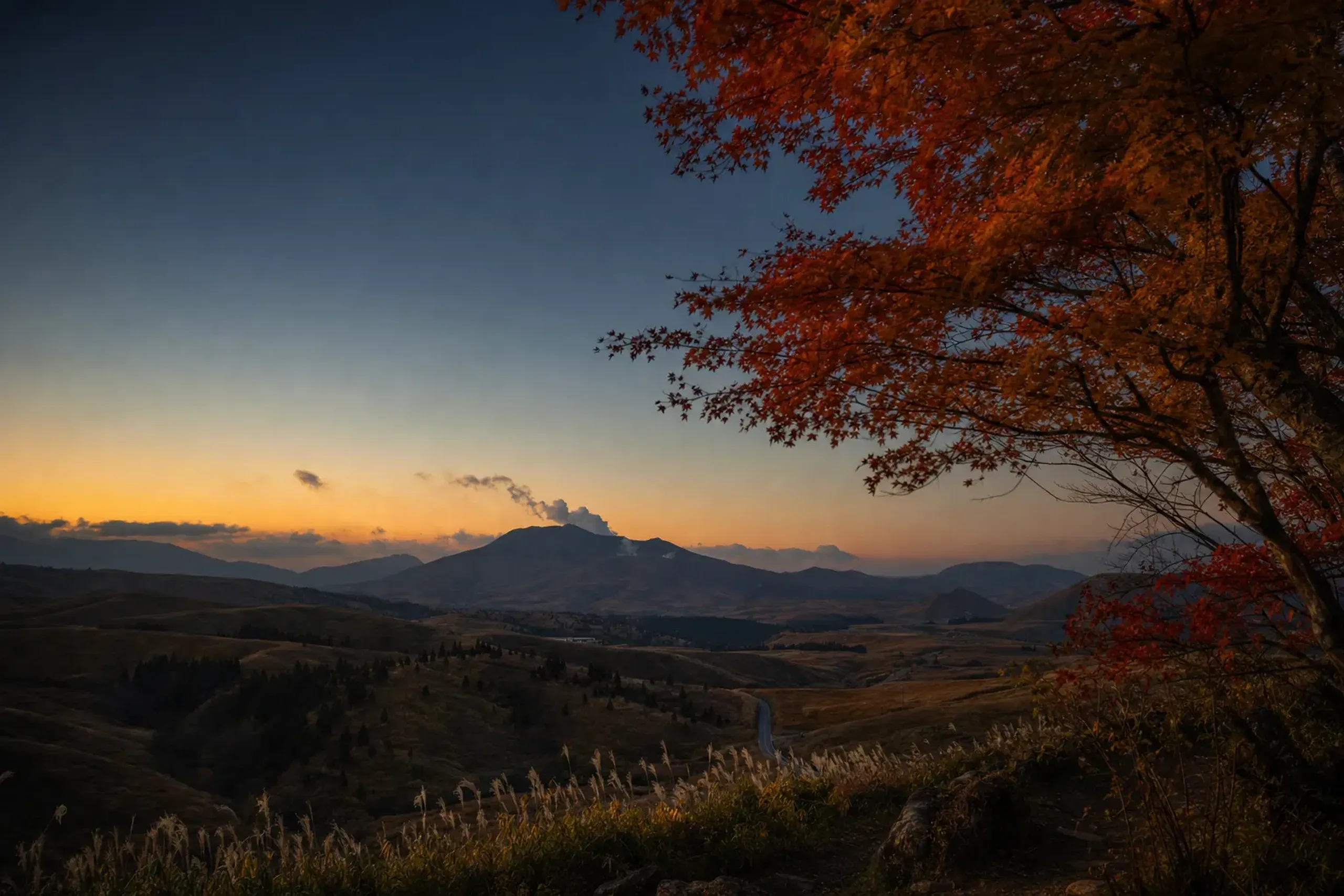 The cone of Mount Aso viewed across highland countryside roughly 20 km south of Kurokawa Onsen under a clear evening sky