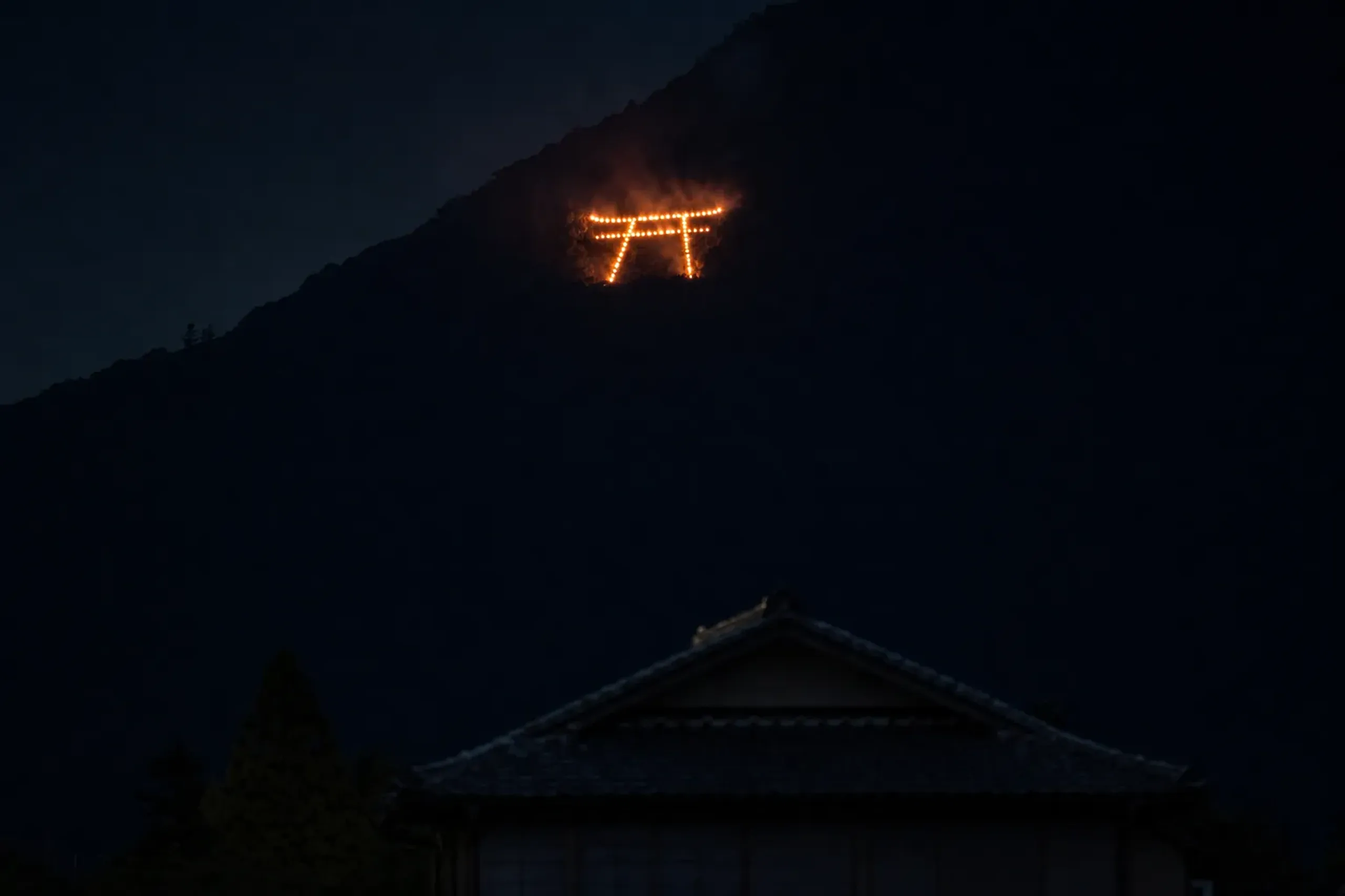 The Toriigata (torii gate) shape outlined in flames on the mountainside near Toriimoto in western Kyoto