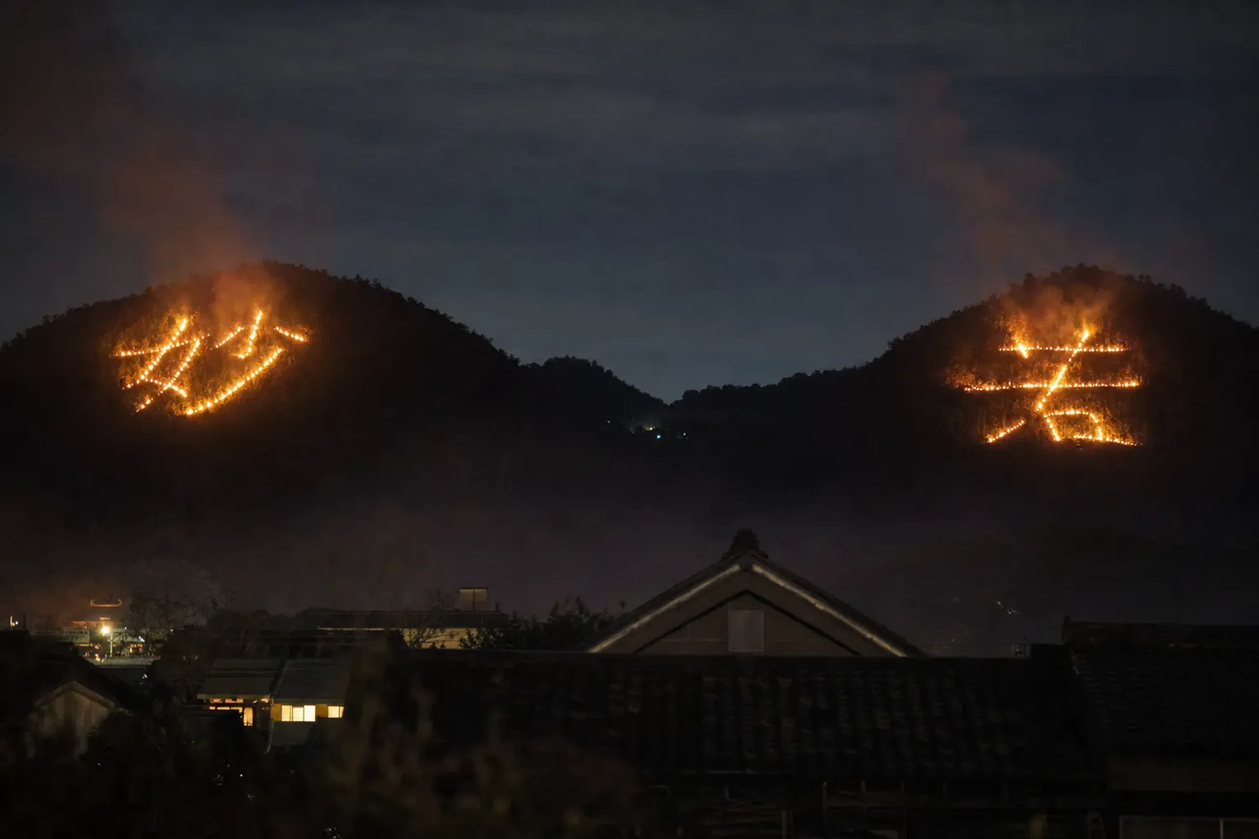 The paired 'Myō' (妙) and 'Hō' (法) bonfire characters glowing on the Matsugasaki hillsides