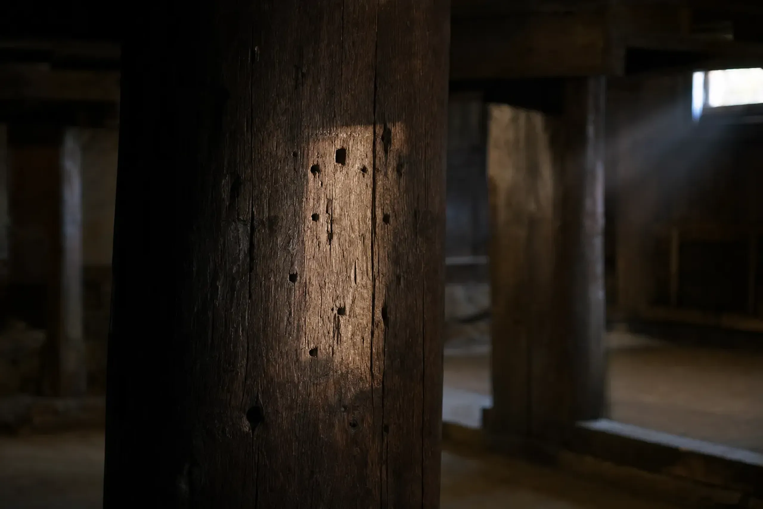 a scarred basement through-pillar inside Matsue Castle keep showing old nail holes where a tablet was once fixed