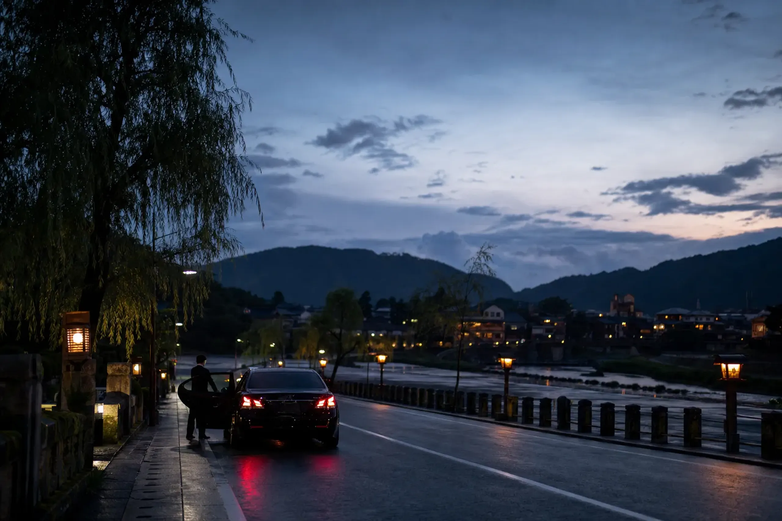 a sleek black private chauffeured car parked on a Nagaoka riverside road under restriction signs during the festival night
