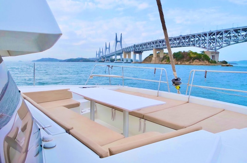 The open deck of the catamaran TAMANO, laid with a table, looking across the Seto Inland Sea to the Great Seto Bridge