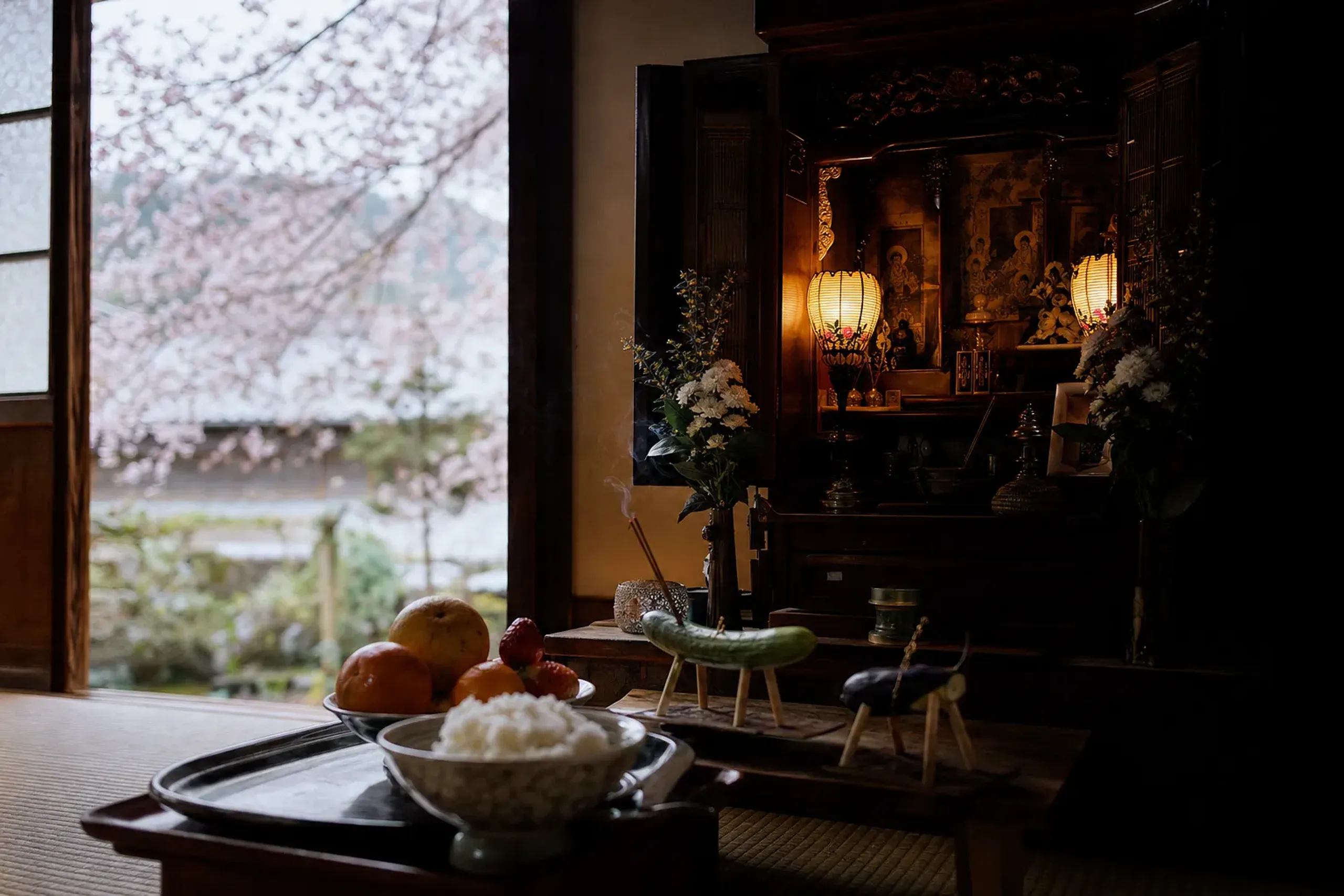 a traditional Japanese home altar with lit lanterns and food offerings arranged for returning ancestral spirits during Obon