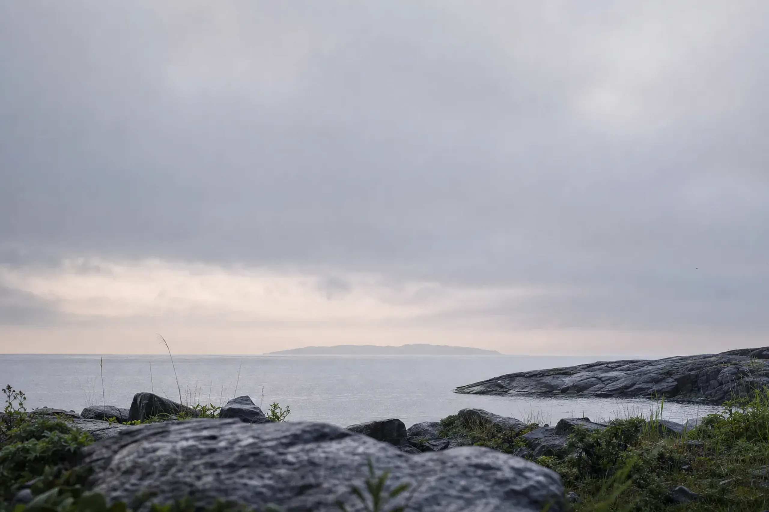 the misty low silhouette of Okinoshima island seen across 48 kilometres of the Genkai Sea from the northern edge of Ōshima at dawn