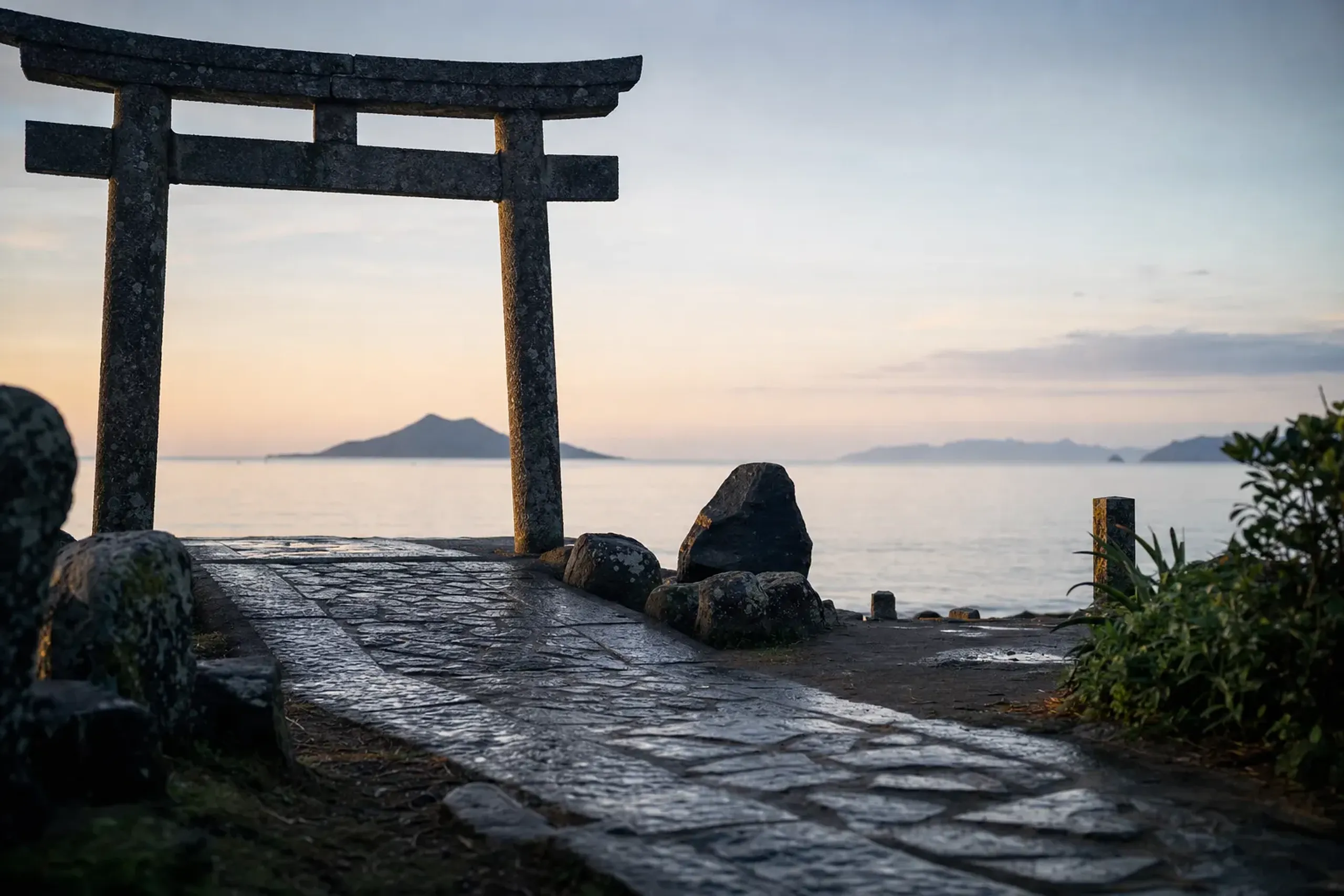 the torii gate and stone approach path of Okitsu-miya's remote worship hall on Ōshima, facing the distant sacred island across the open sea