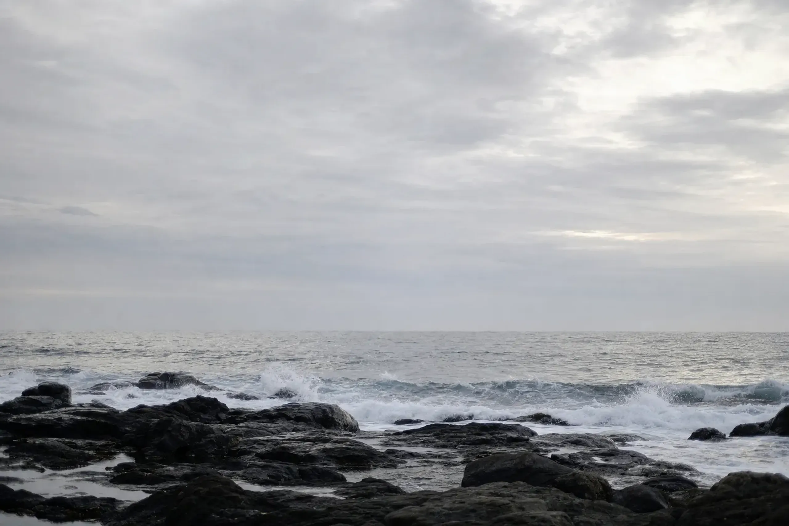 the cold grey waves of the Genkai Sea breaking on a rocky shoreline where shio-gori sea purification would take place