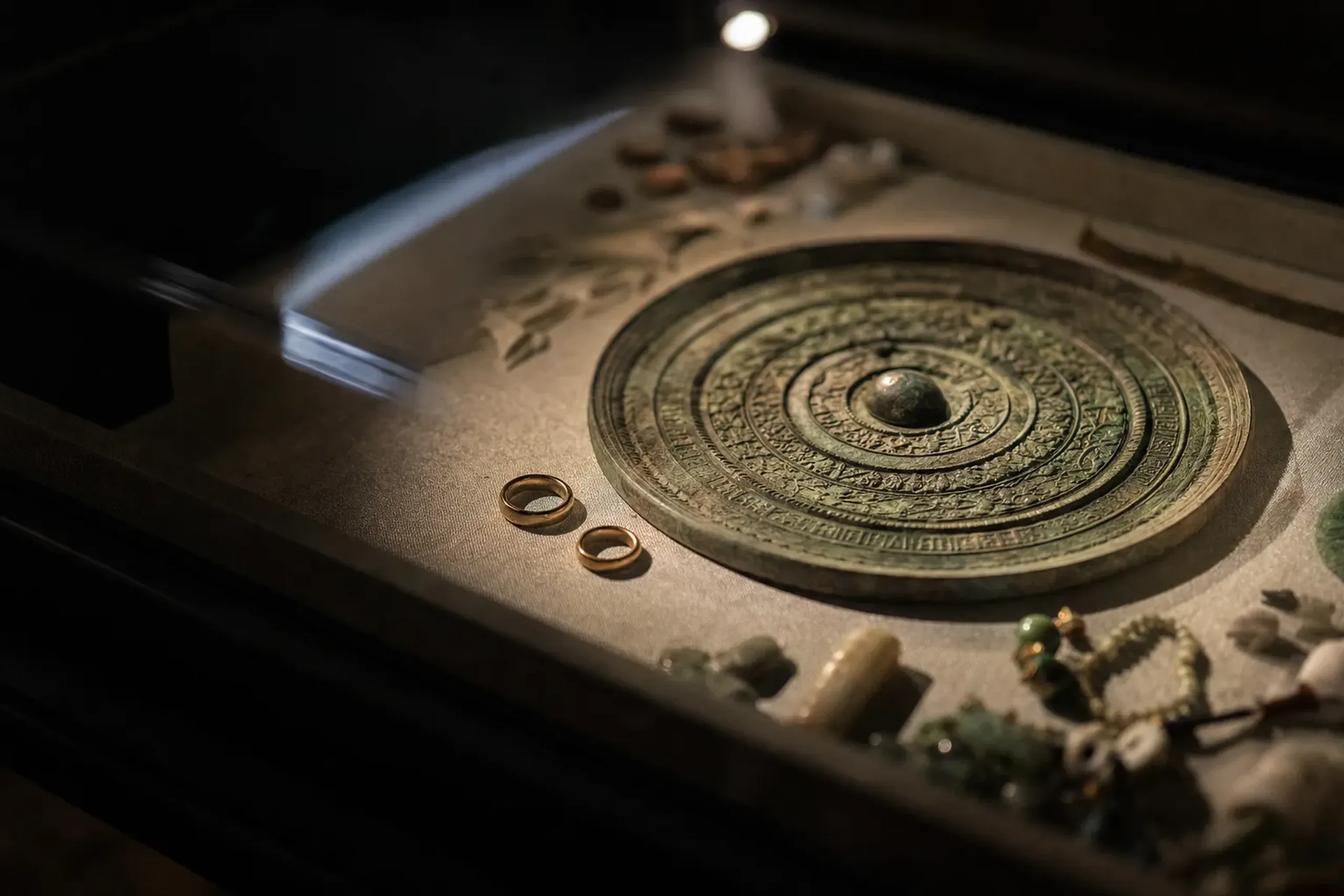 an ancient bronze mirror and gold rings among votive offerings excavated from Okinoshima, displayed in the Shinpōkan treasure hall at Hetsu-miya