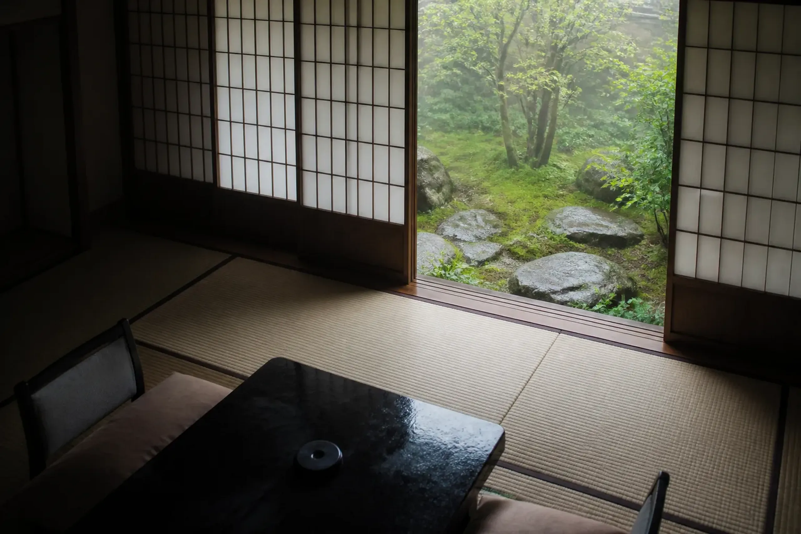 Empty tatami room with shoji screens and a moss garden view in a Hakone ryokan