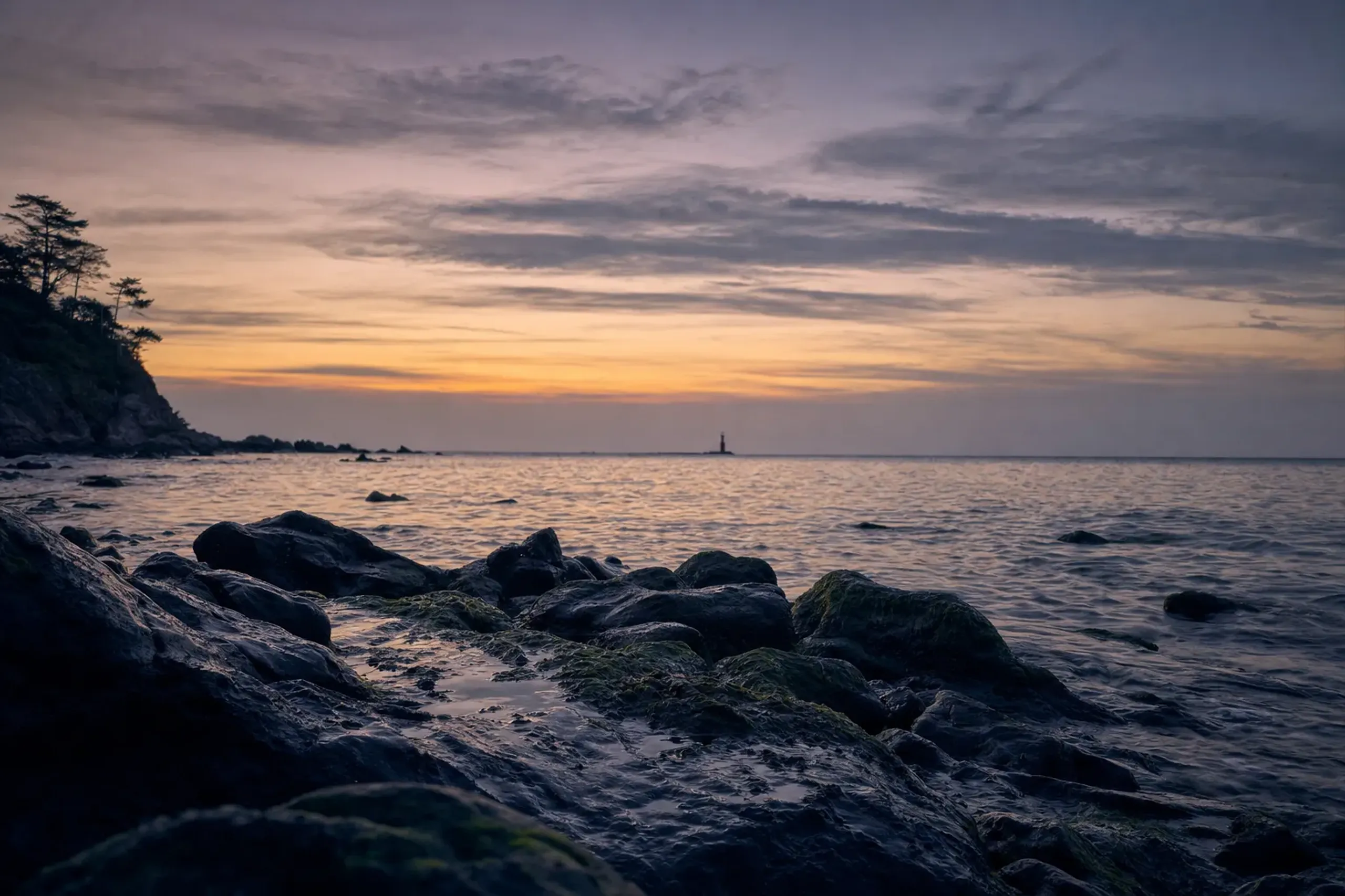 The rocky shoreline of Benten Island at Shimoda looking out over the bay toward the open sea at dusk