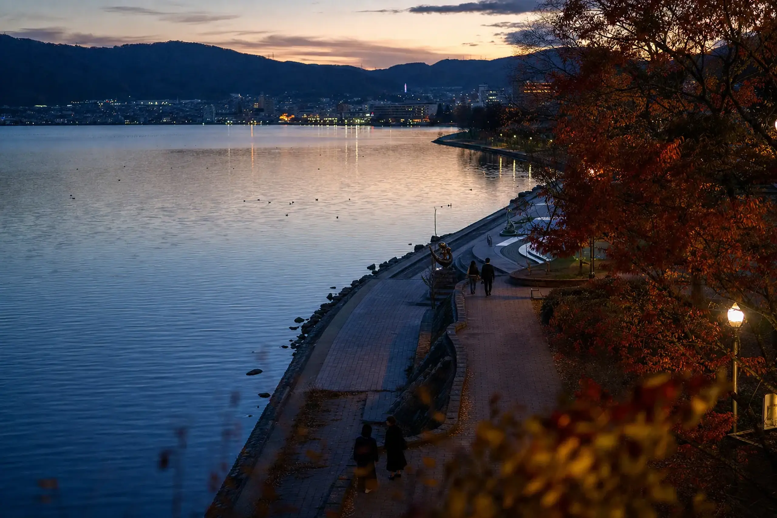 The lakeside path near JR Kami-Suwa Station leading toward Kohan Park along the shore of Lake Suwa at twilight