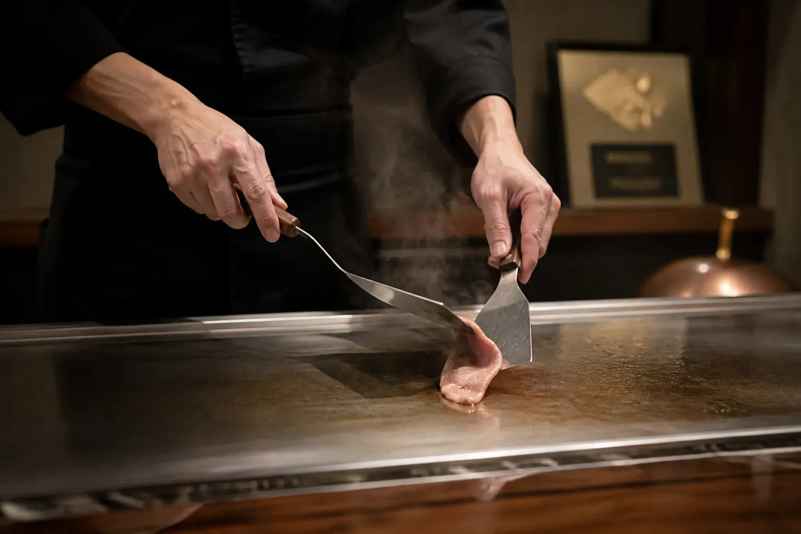 Teppanyaki counter scene with a certification plaque displayed at a Kobe beef restaurant