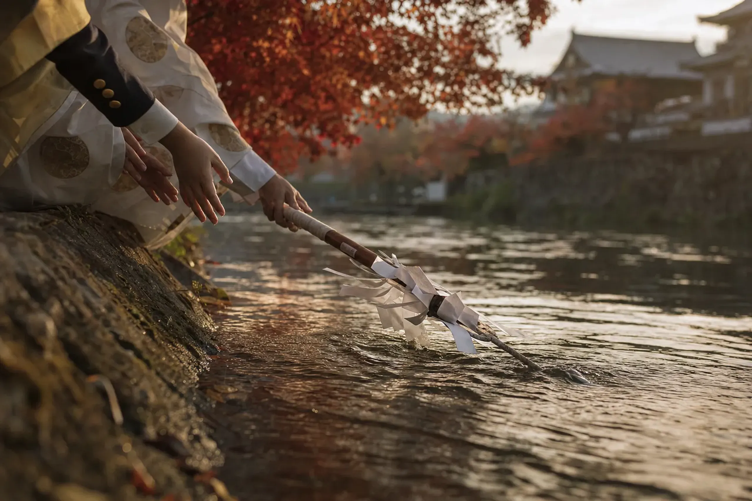 The carved and bound sacred hoko halberd being lowered into the brown current of the Dōjima River near Tenmangū shrine during the Hoko-nagashi Shinji rite