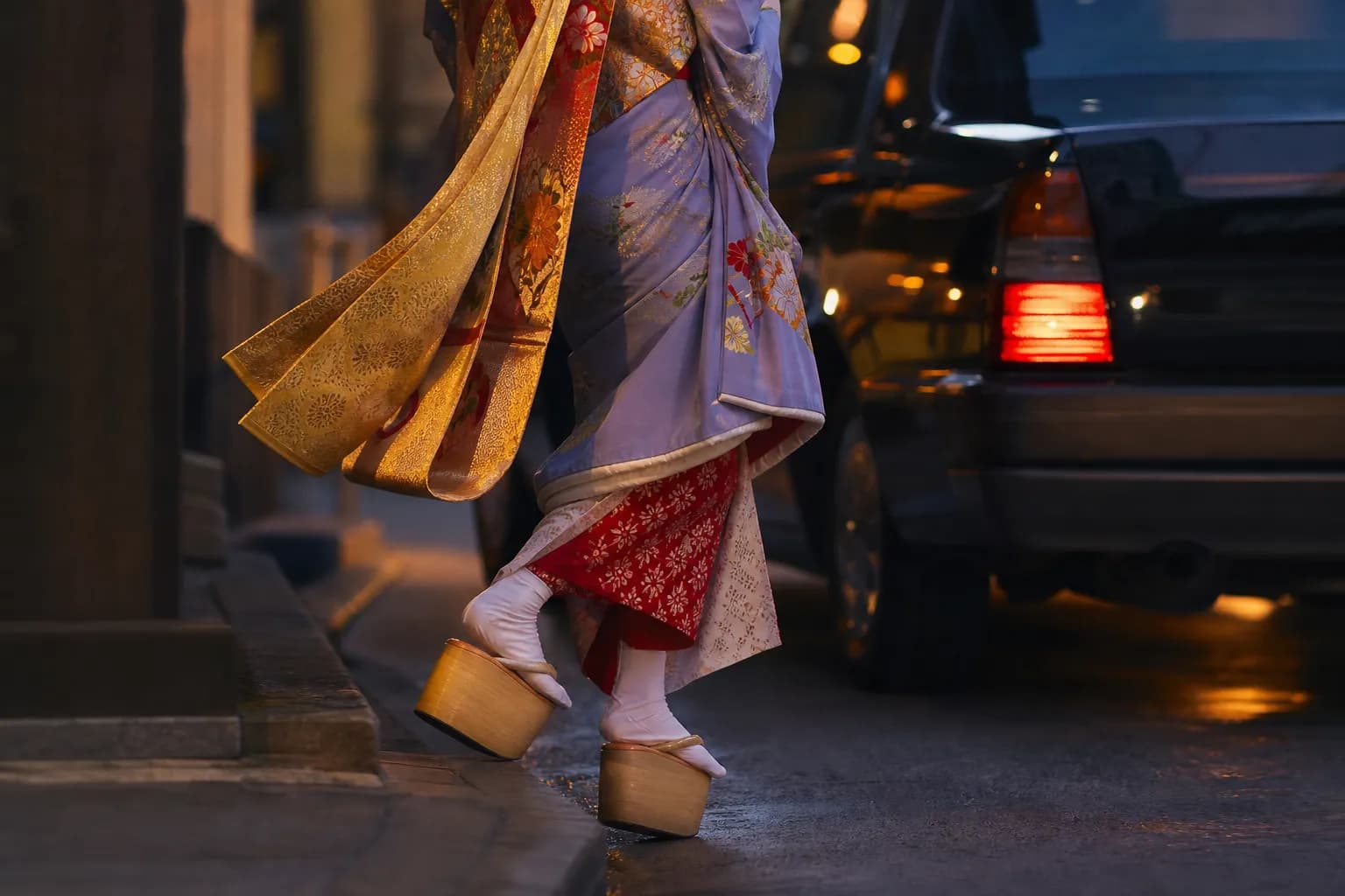 Close-up of a maiko kimono and obi beside a modern taxi in Japan