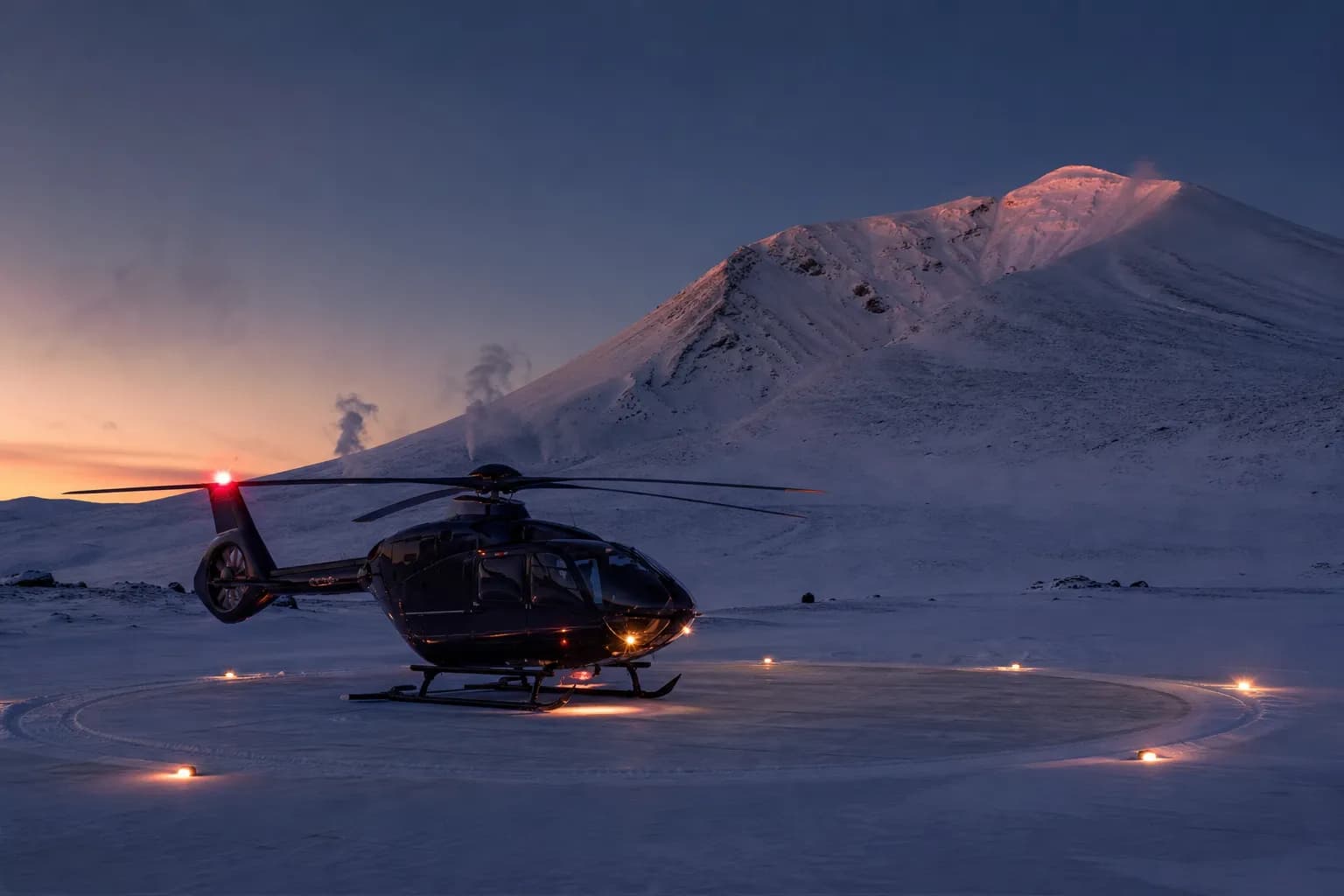 A private helicopter parked on a snow-cleared pad below the peak of Mount Asahidake at dusk in the Daisetsuzan volcanic group, Hokkaido
