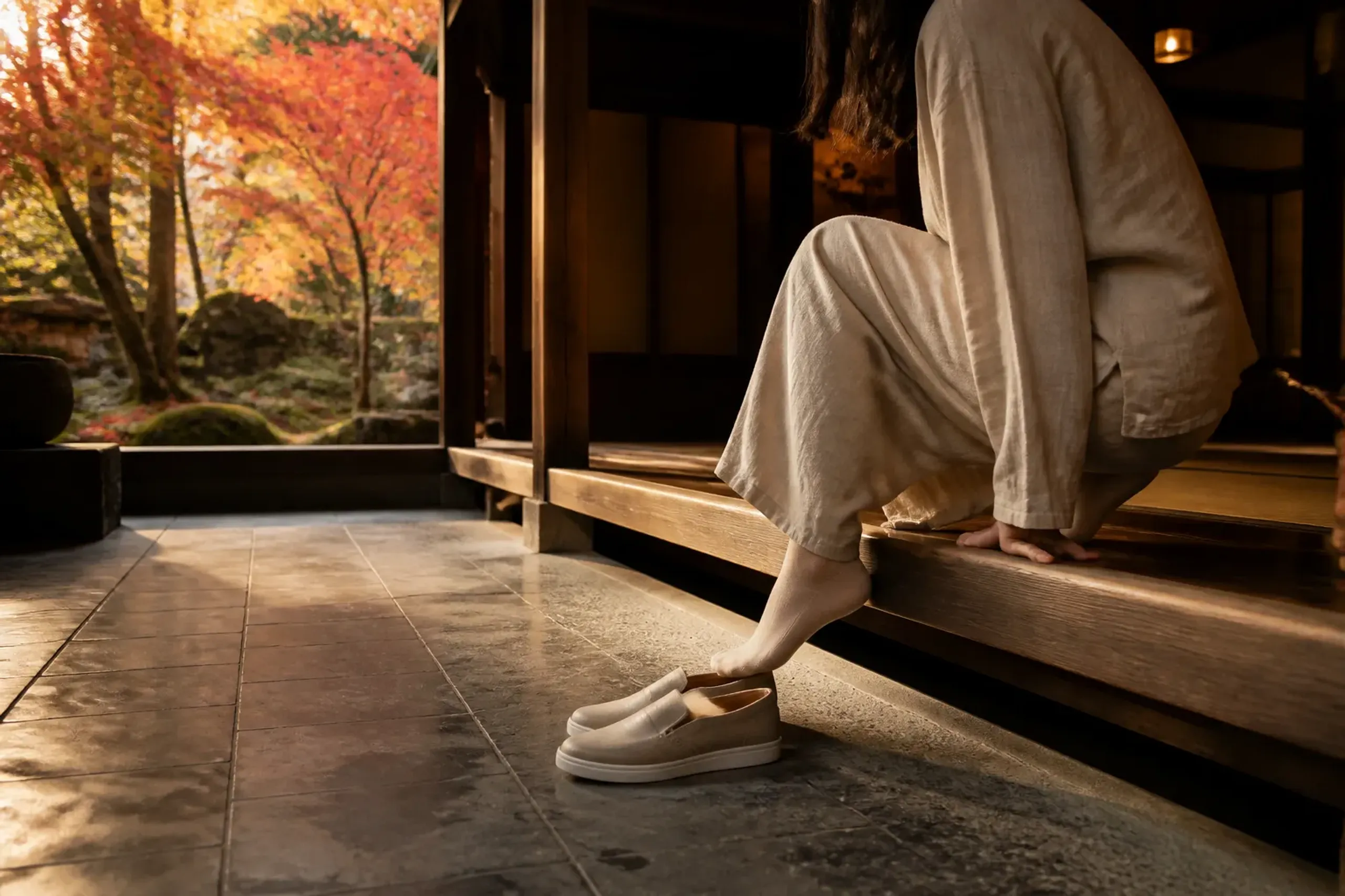 Traveler in neutral clothing removing shoes at a traditional Japanese entrance