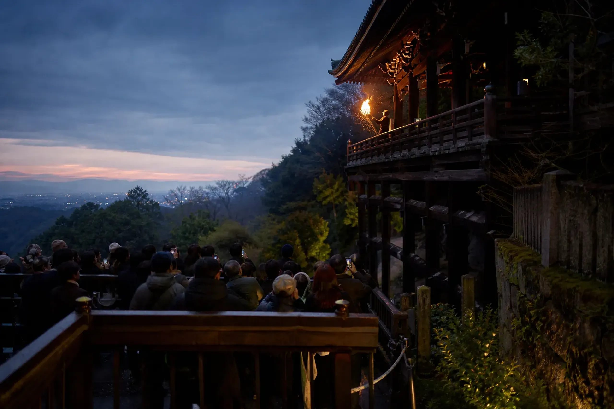Crowds stand behind bamboo fencing below Nigatsu-dō during Omizutori torch viewing