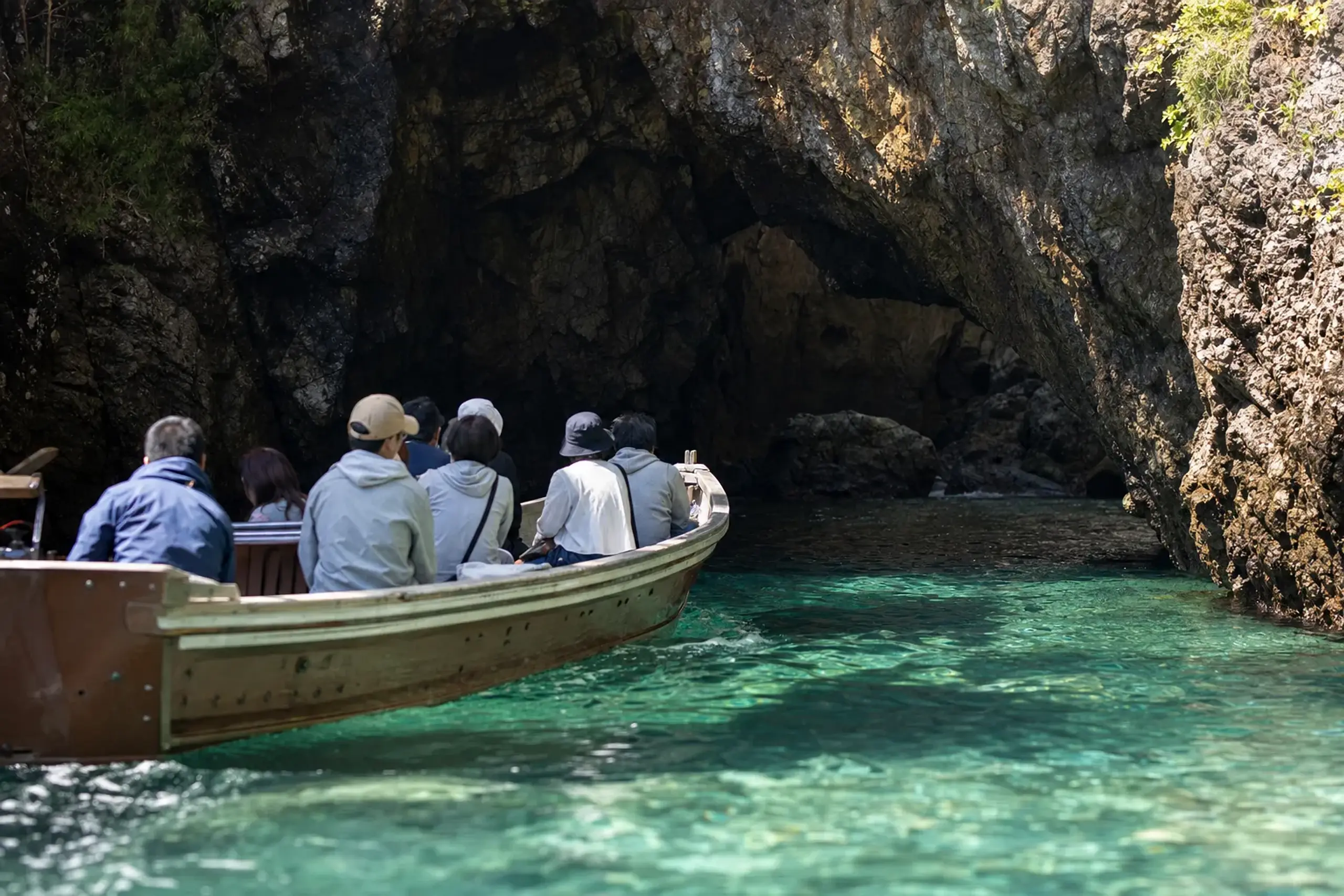 A sightseeing boat gliding into a sea-eroded cave along the Uradome Coast near Tottori