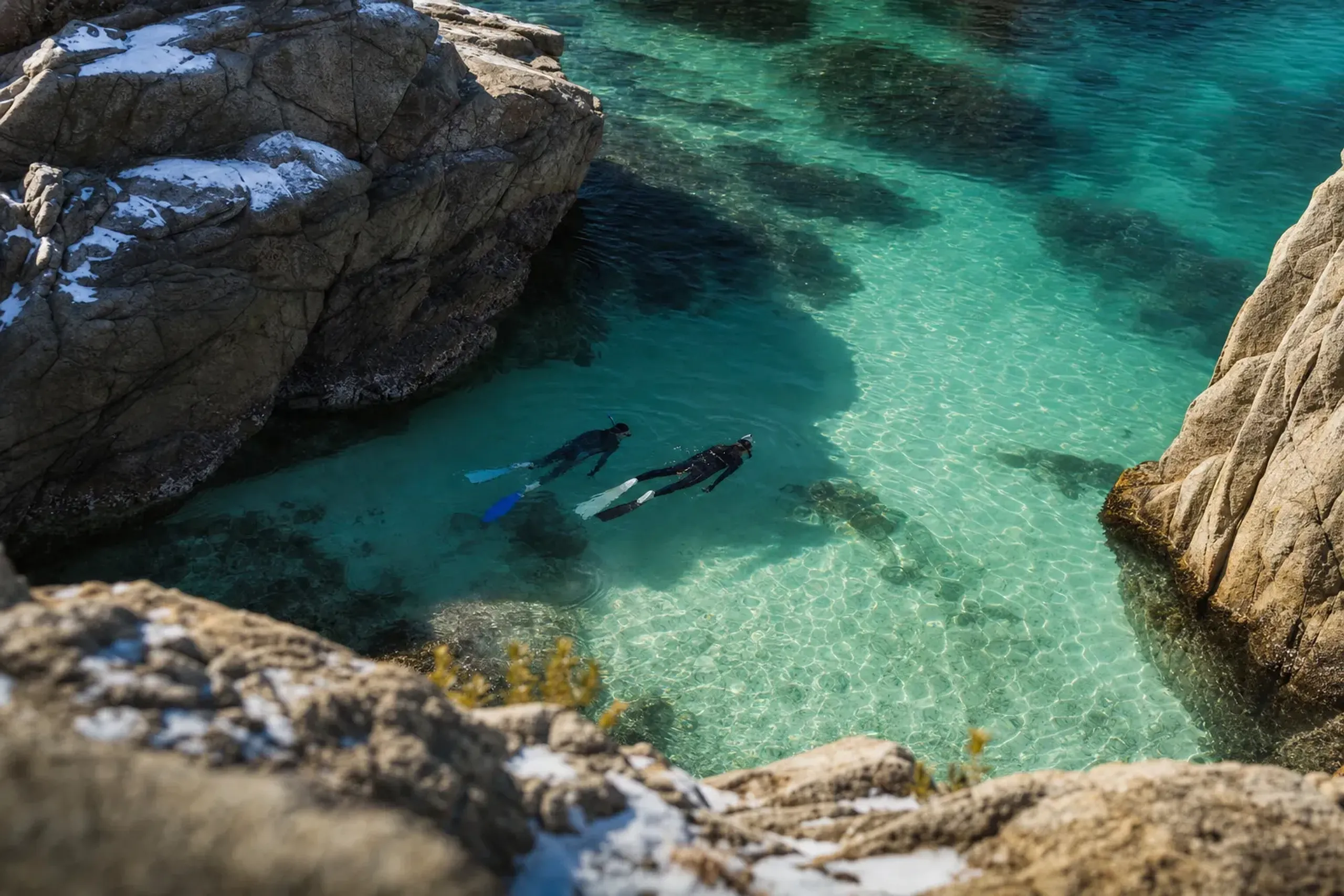 Snorkelers in the clear summer waters between the rock faces of the Uradome Coast