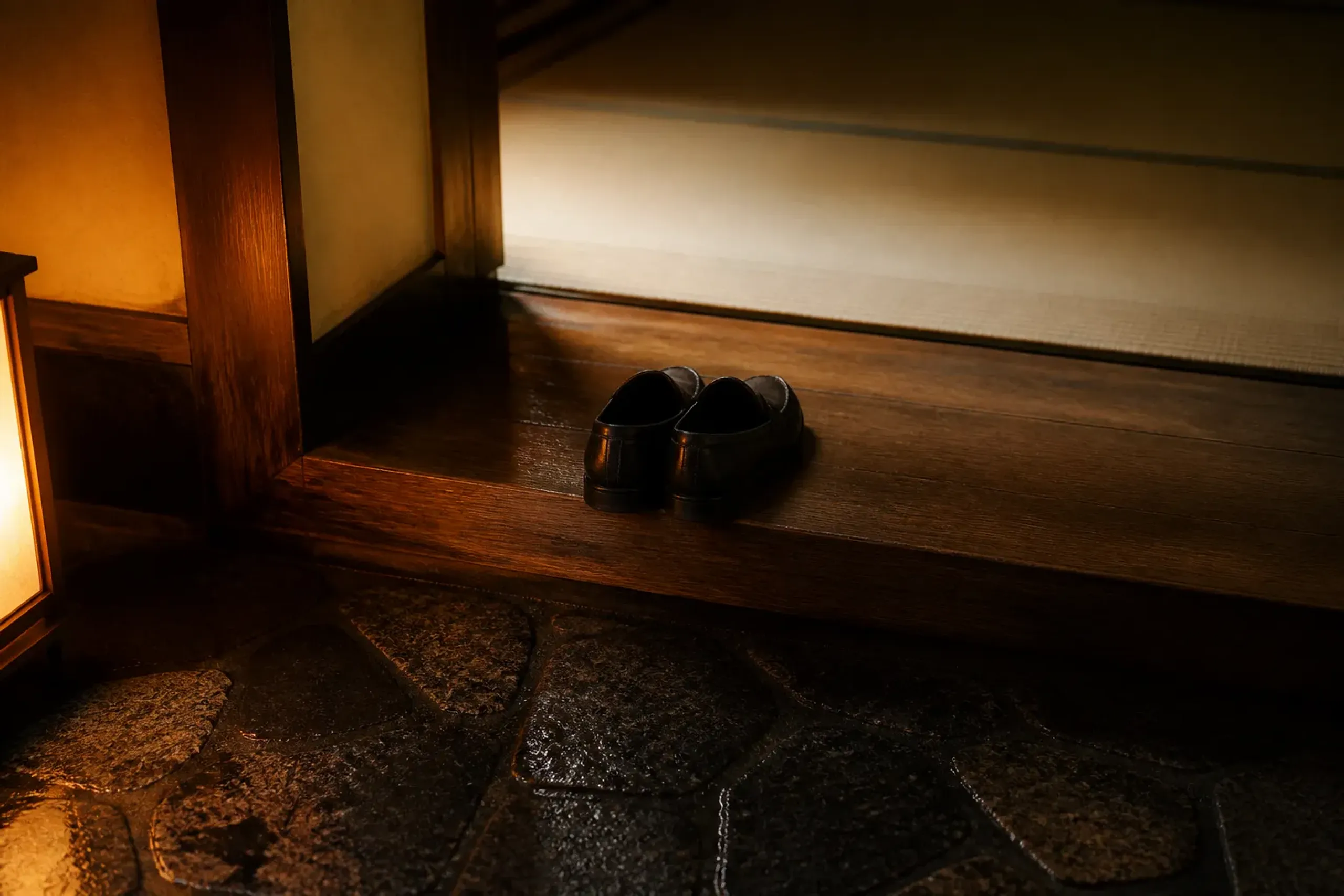 Slip-on loafers removed and placed neatly at a wooden ryokan genkan entrance in Japan