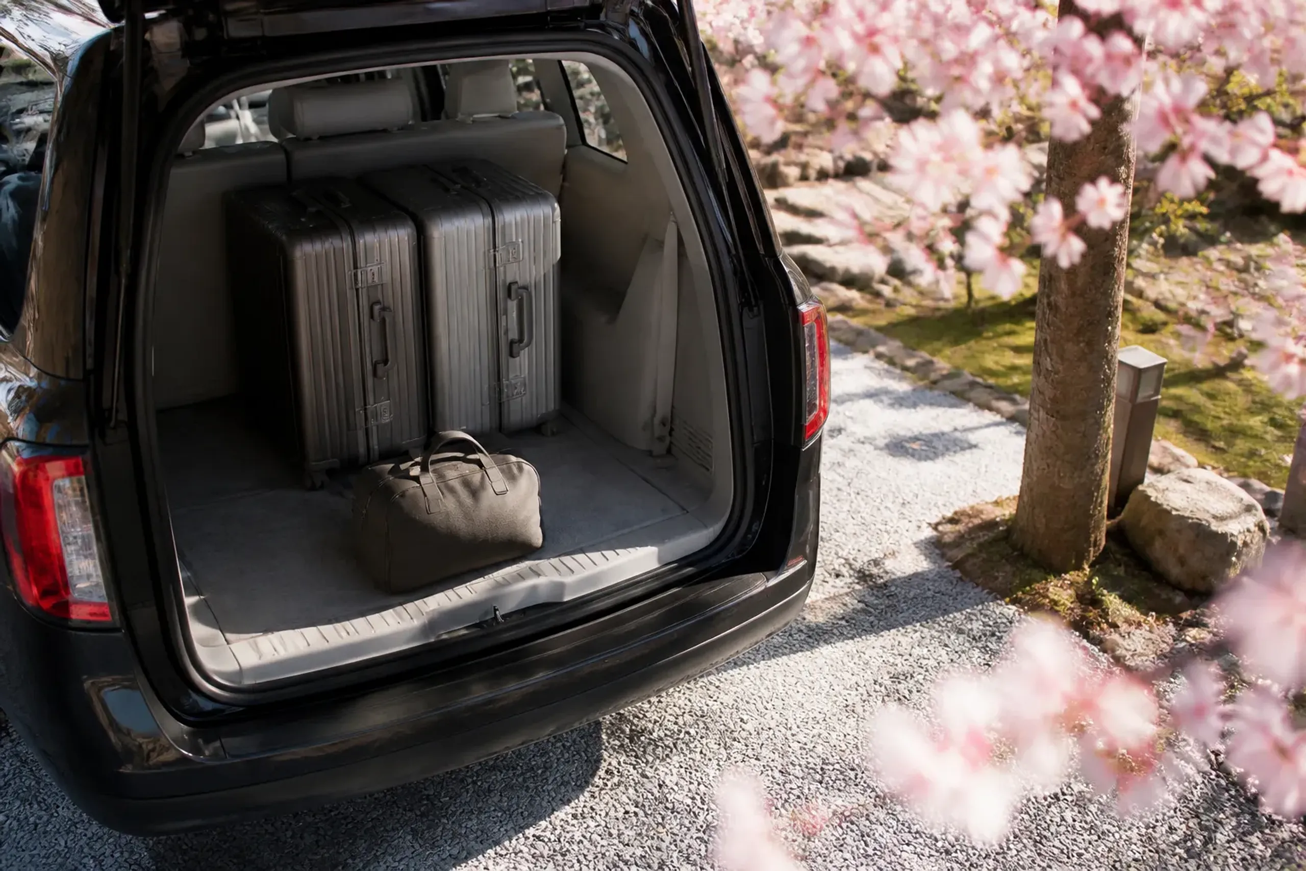 Large suitcases secured in a luxury van with a small overnight bag nearby