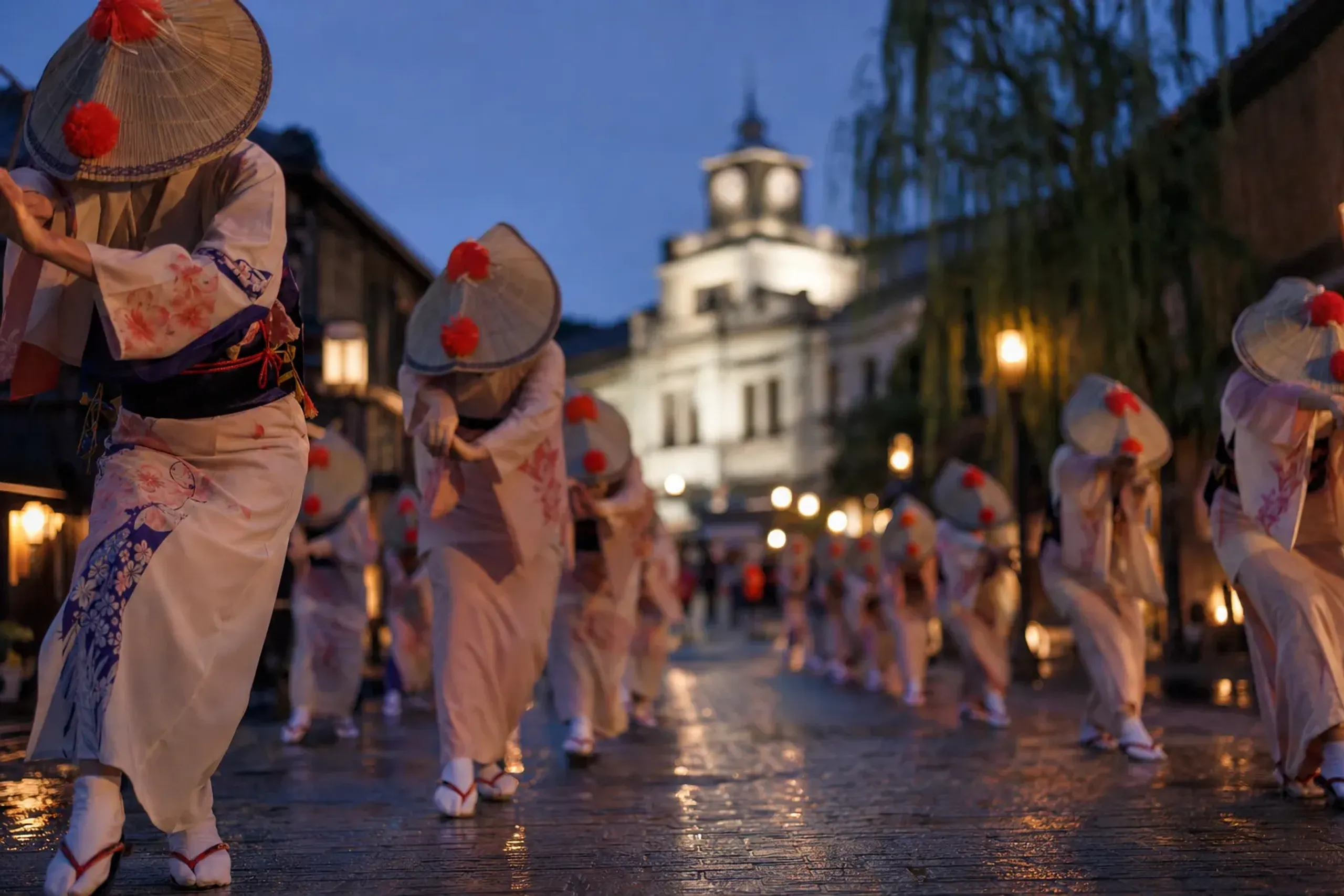 Rows of Yamagata Hanagasa dancers in straw hats trimmed with red safflowers advancing down the closed main street at dusk toward the old Bunshokan prefectural office building