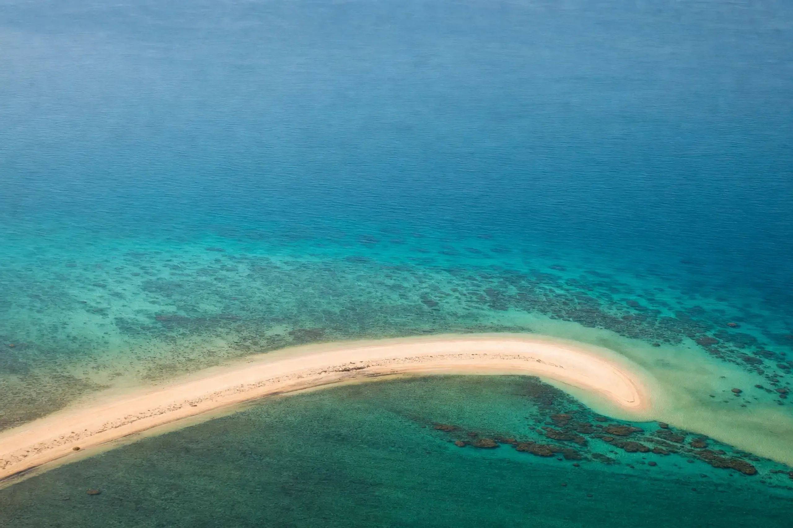 the curved white ribbon of the Yurigahama sandbar rising from the reef, surrounded on every side by clear turquoise water