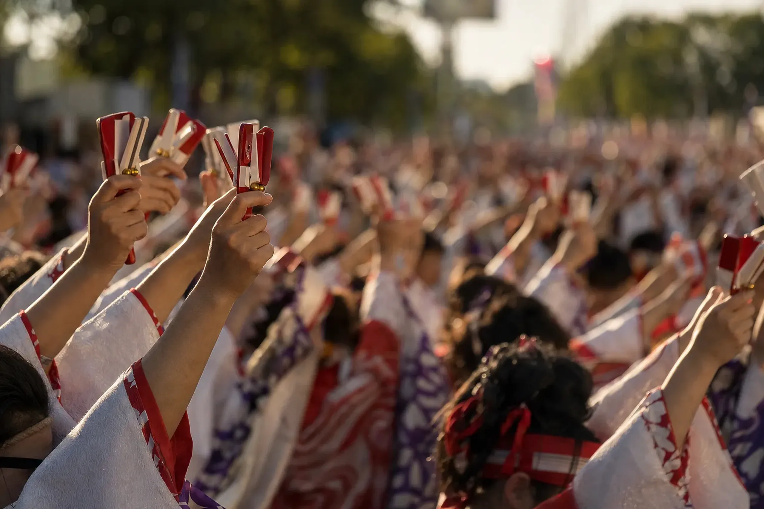 A row of red-and-white wooden naruko clappers held aloft by participating dancers at the YOSAKOI Soran Festival