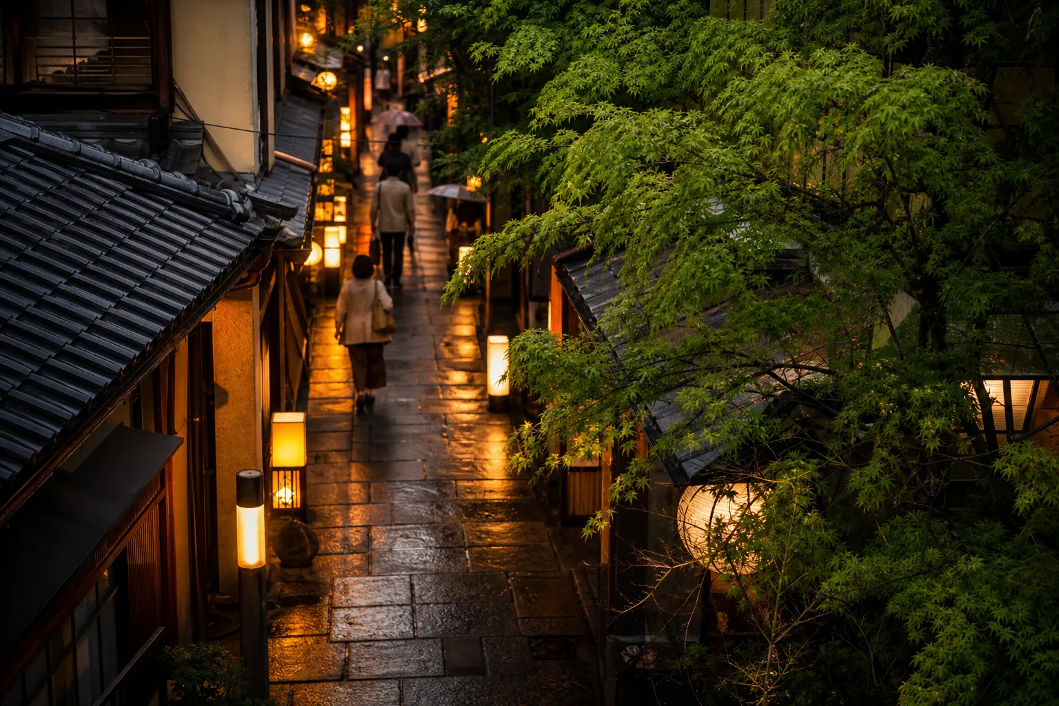 Lantern-lit Hozenji Yokocho alley in Osaka with wet stone pavement reflecting warm light
