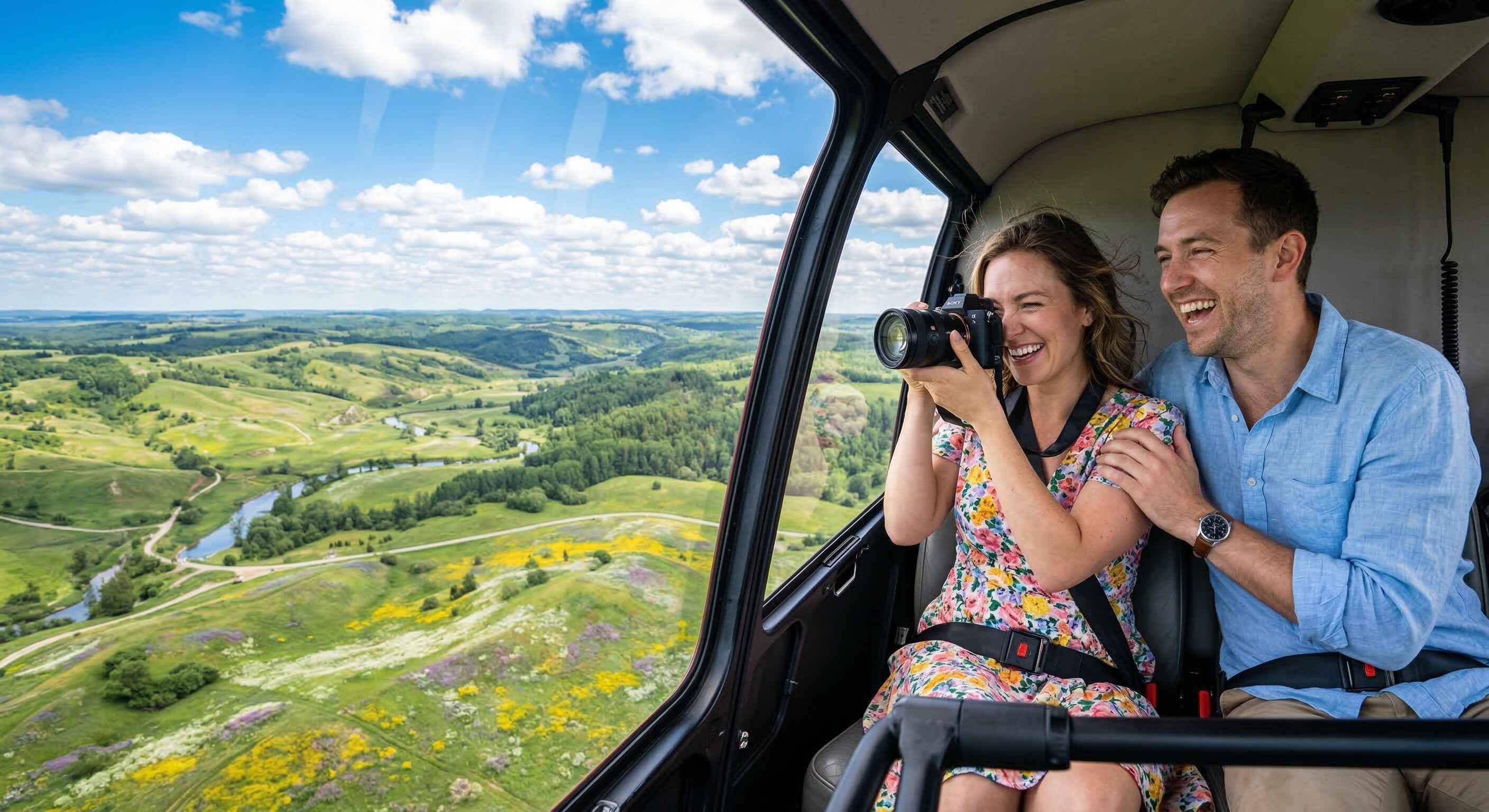 A couple smiling and taking a photograph out the window of a helicopter during a clear spring day.