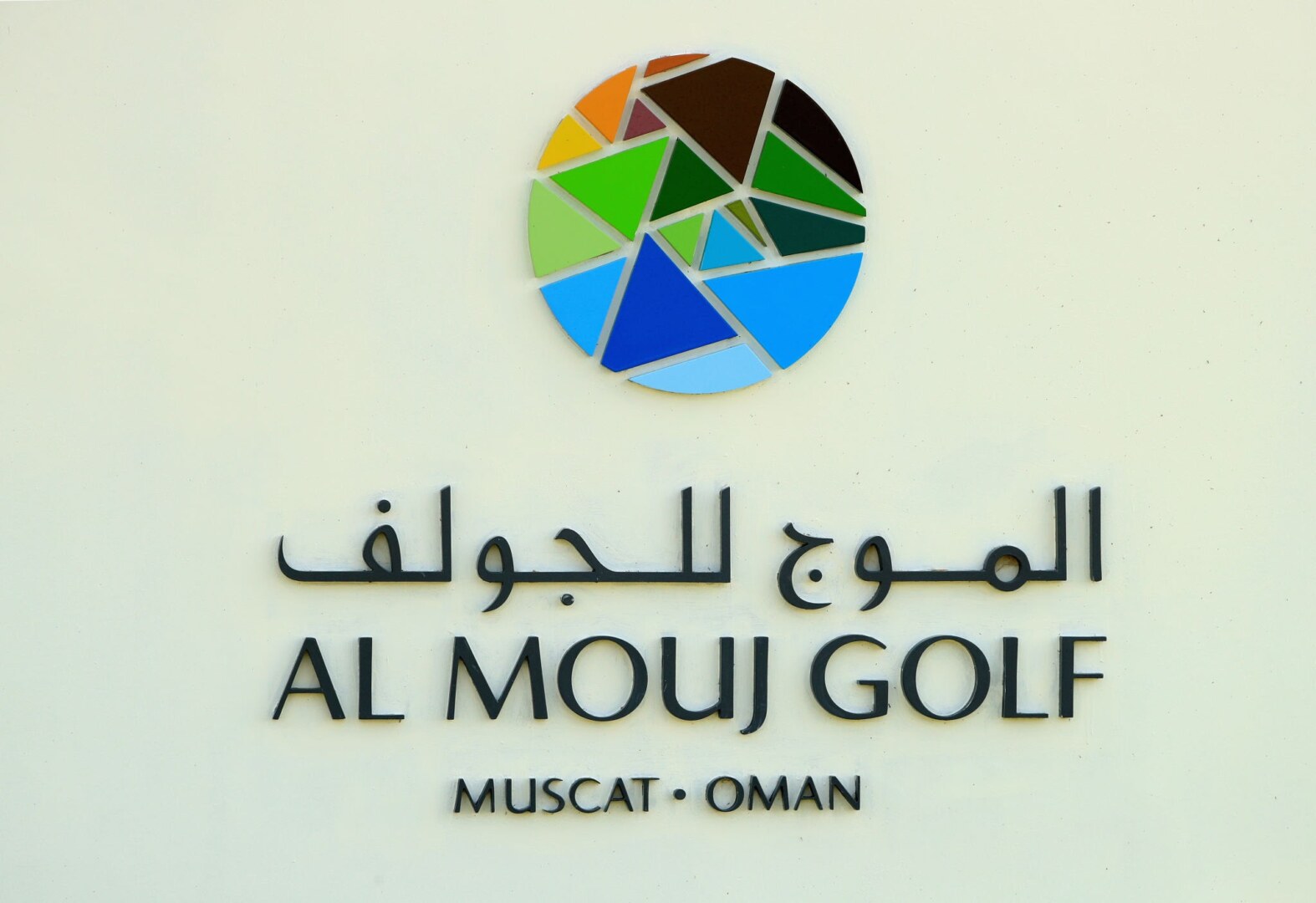 The official colorful logo sign for Al Mouj Golf located in Muscat, Oman.