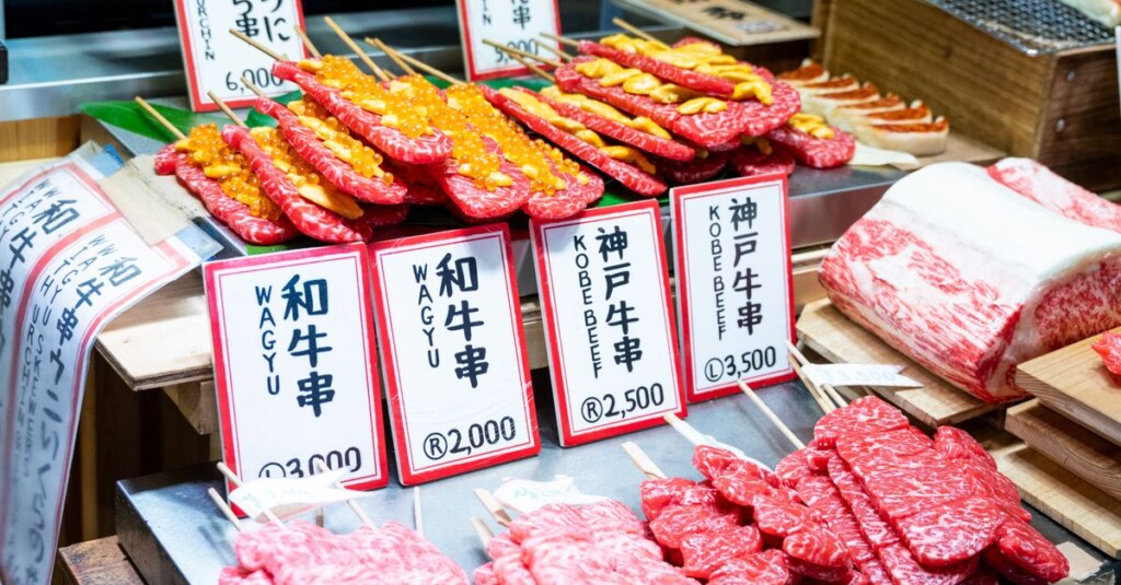Wagyu beef skewers on display at a Japanese market with price signs in yen.