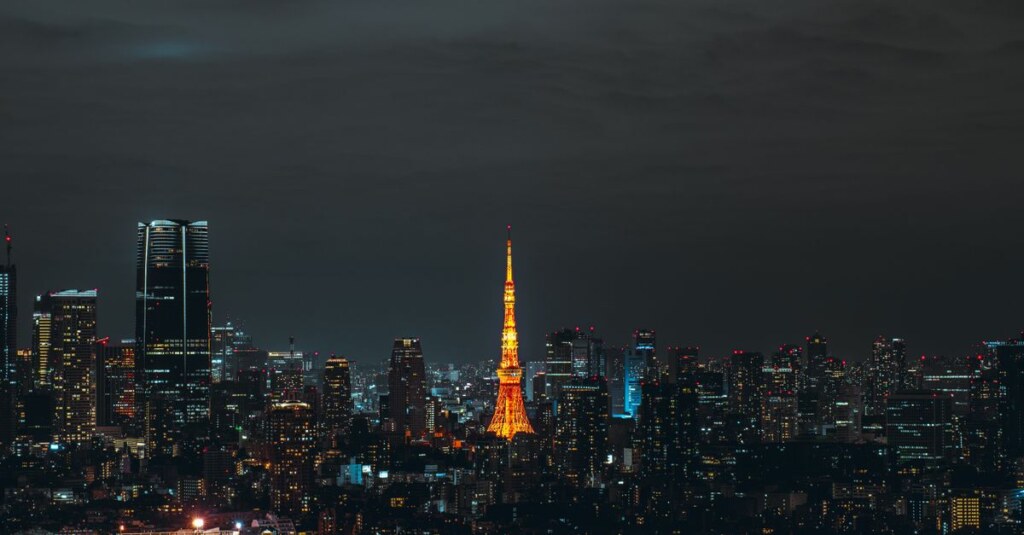 Nighttime city skyline with an orange-lit tower standing tall in the center (Tokyo Tower).