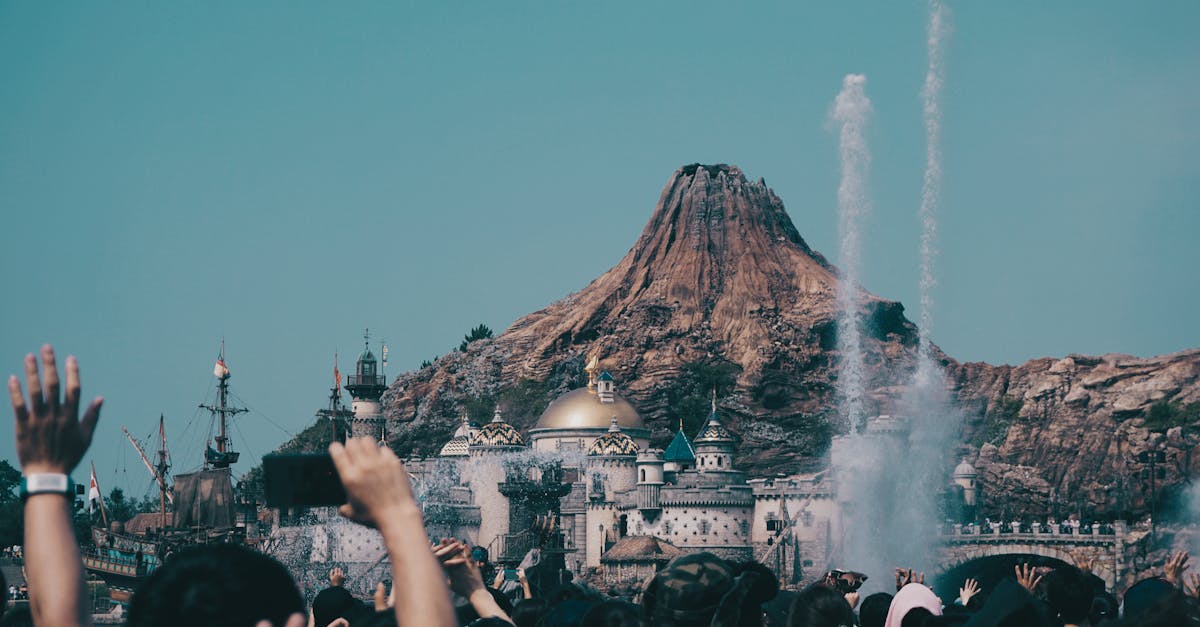 Vibrant theme park scene with a crowd near a volcano and dome during the day. — Photo by Yan - on Pexels