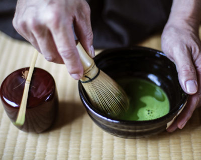 Traditional Japanese Tea Ceremony, man using whisk to prepare green tea.